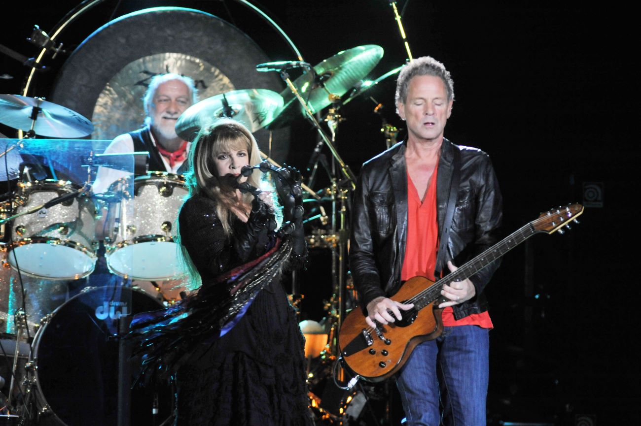 Mick Fleetwood plays drums, Stevie Nicks holds a tambourine and Lindsey Buckingham plays guitar.
