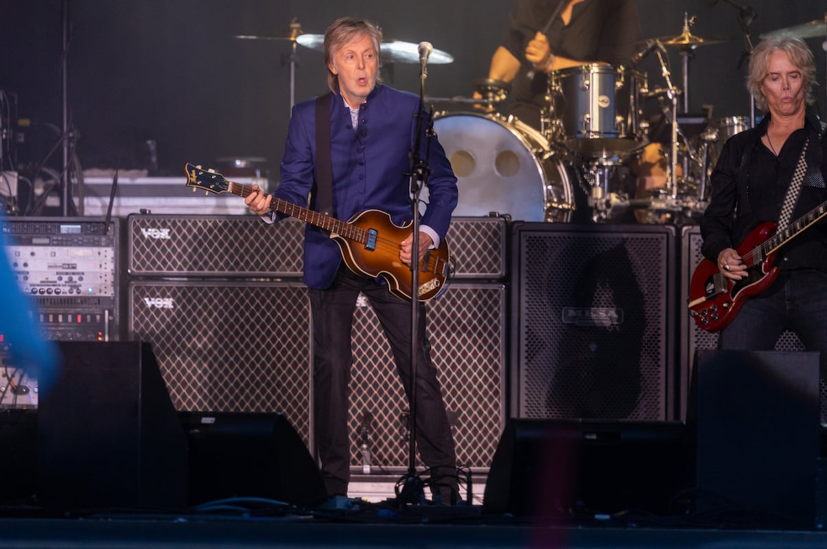 Paul McCartney plays the guitar and sings on stage