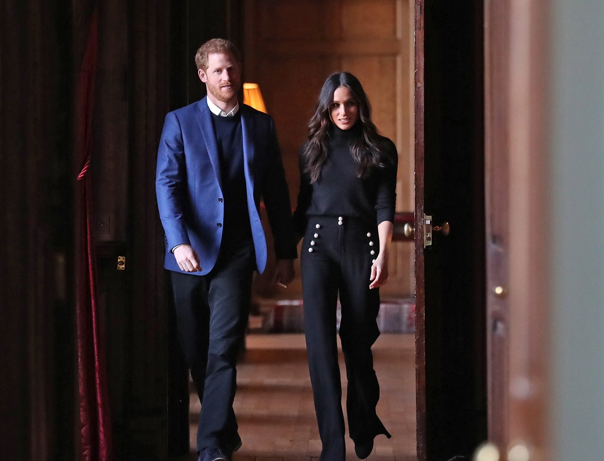 Prince Harry and Meghan Markle walk through the corridors of the Palace of Holyroodhouse on their way to a reception for young 