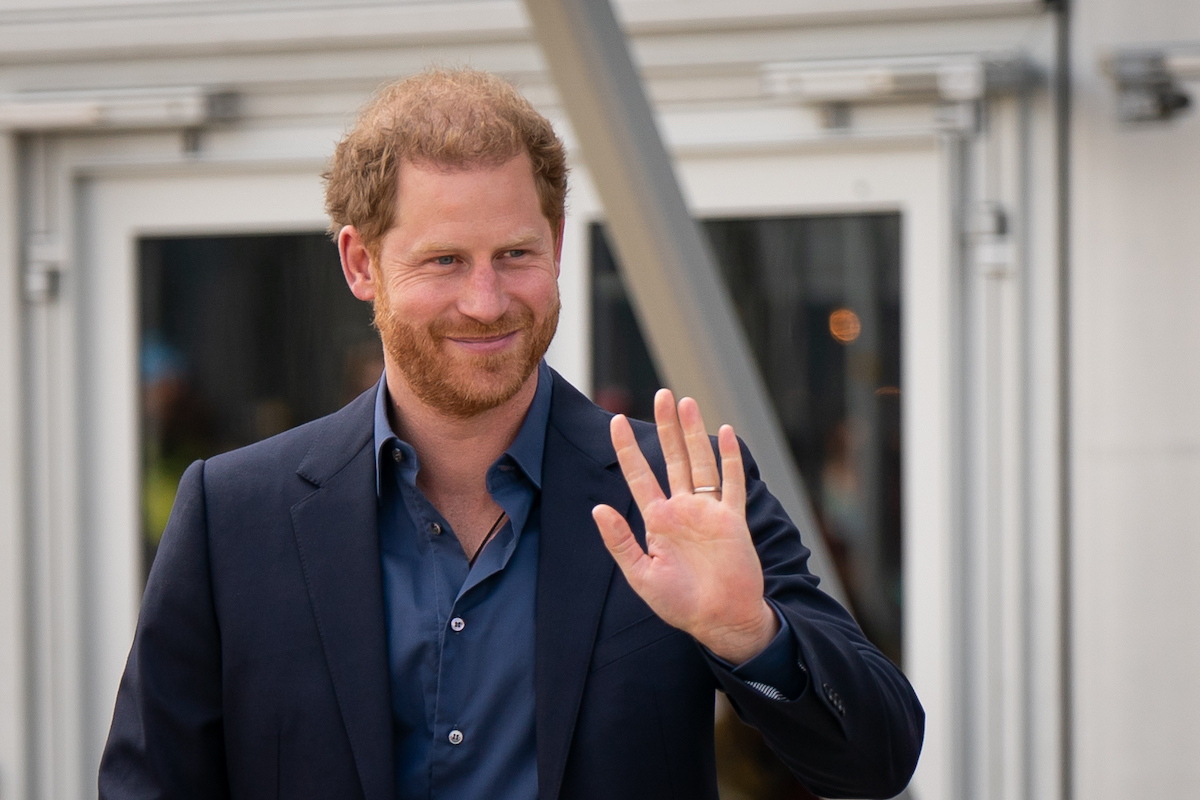 Prince Harry, whose 'highly unlikely' to return his book advance and shelve his memoir according to royal expert Katie Nicholl, waves wearing a suit jacket