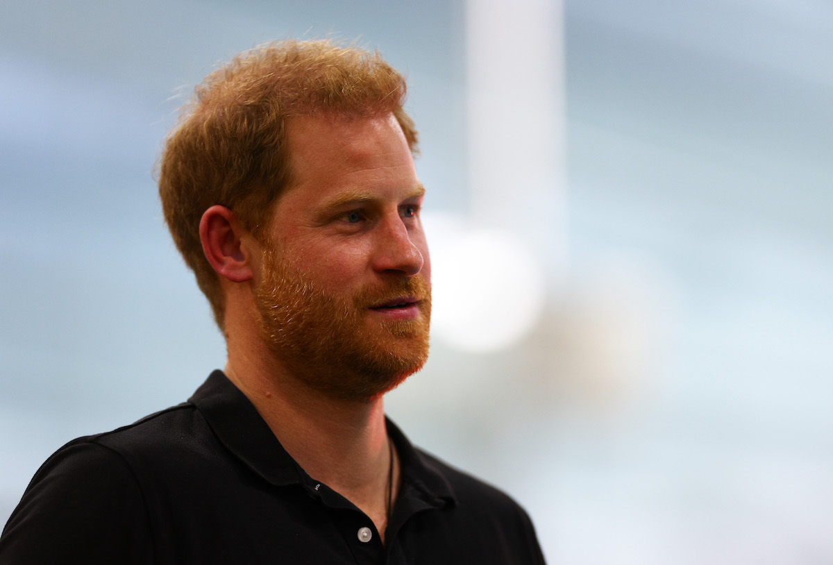 Prince Harry, who it is 'highly unlikely' he will return his memoir advance and shelve his book, according to a royal expert, looks on wearing a black polo shirt