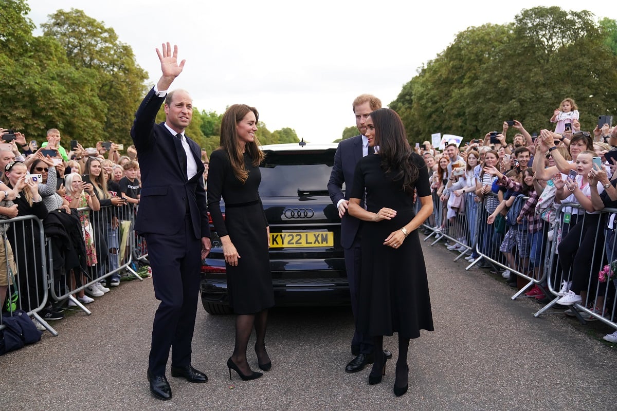 Le prince William, Kate Middleton, le prince Harry et Meghan Markle sourient et saluent après avoir salué les membres du public lors de la longue marche au château de Windsor