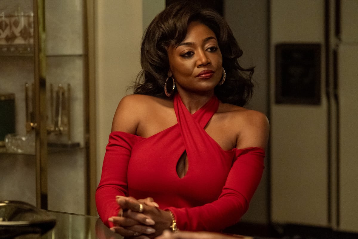 Patina Miller as Raq Thomas in a blood red top sitting at the table in 'Power Book III: Raising Kanan'