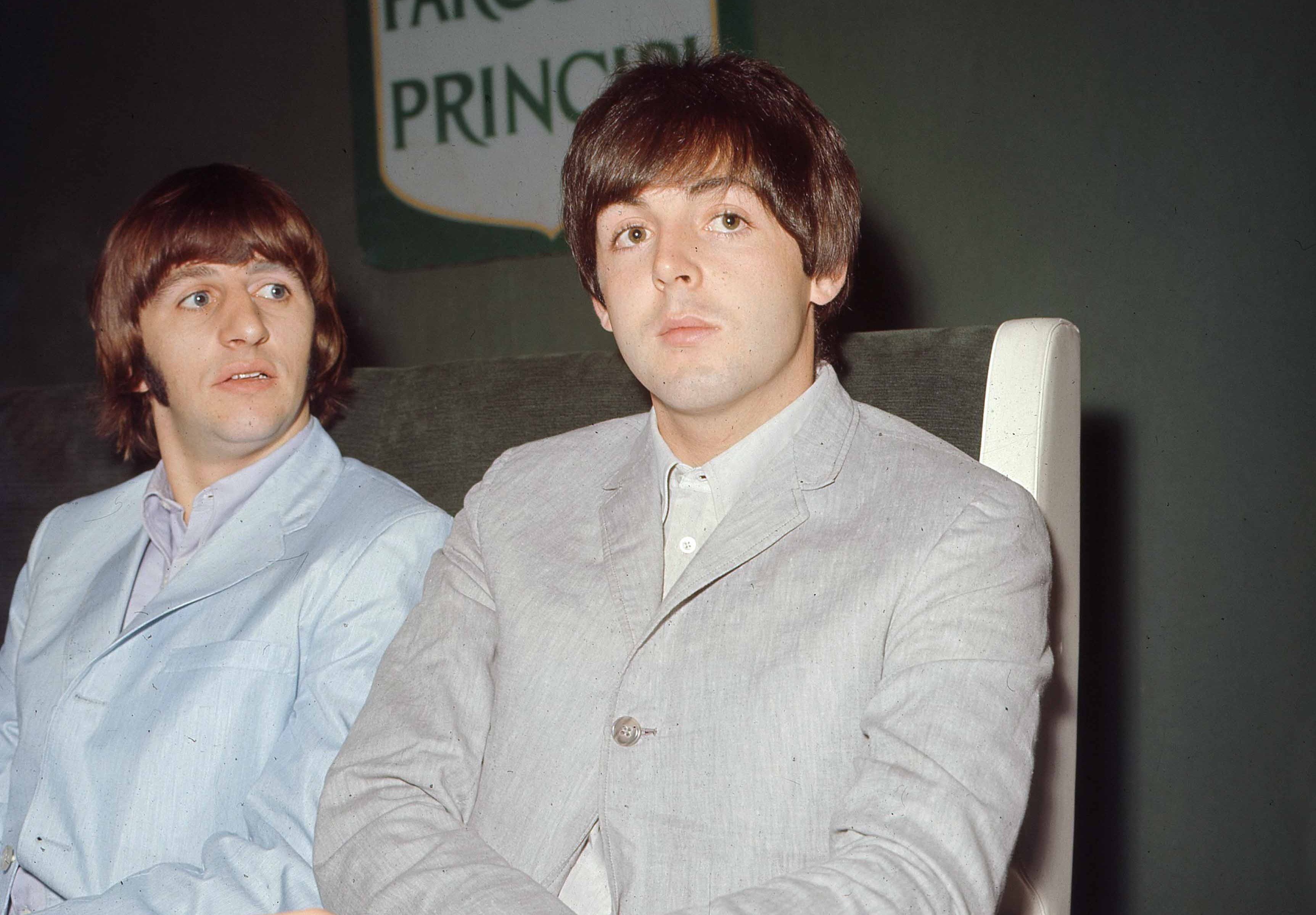 Ringo Starr and Paul McCartney sit at a table together.