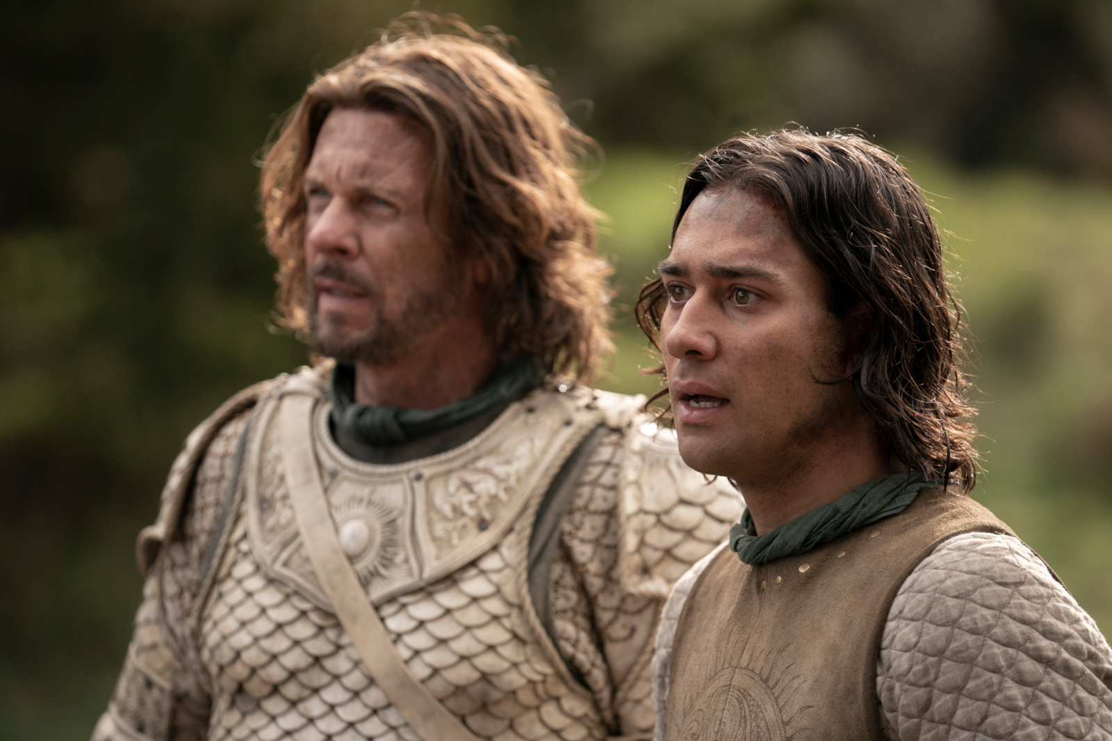 Lloyd Owen and Maxim Baldry as Elendil and Isildur in 'The Rings of Power' Episode 6 for our article about its Easter Eggs. They're wearing golden armor and look shocked.