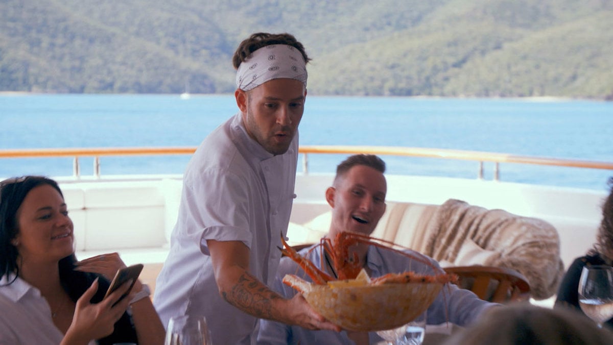 Chef Ryan McKeown from 'Below Deck Down Under' brings a bowl filled with crab to the guests' table.