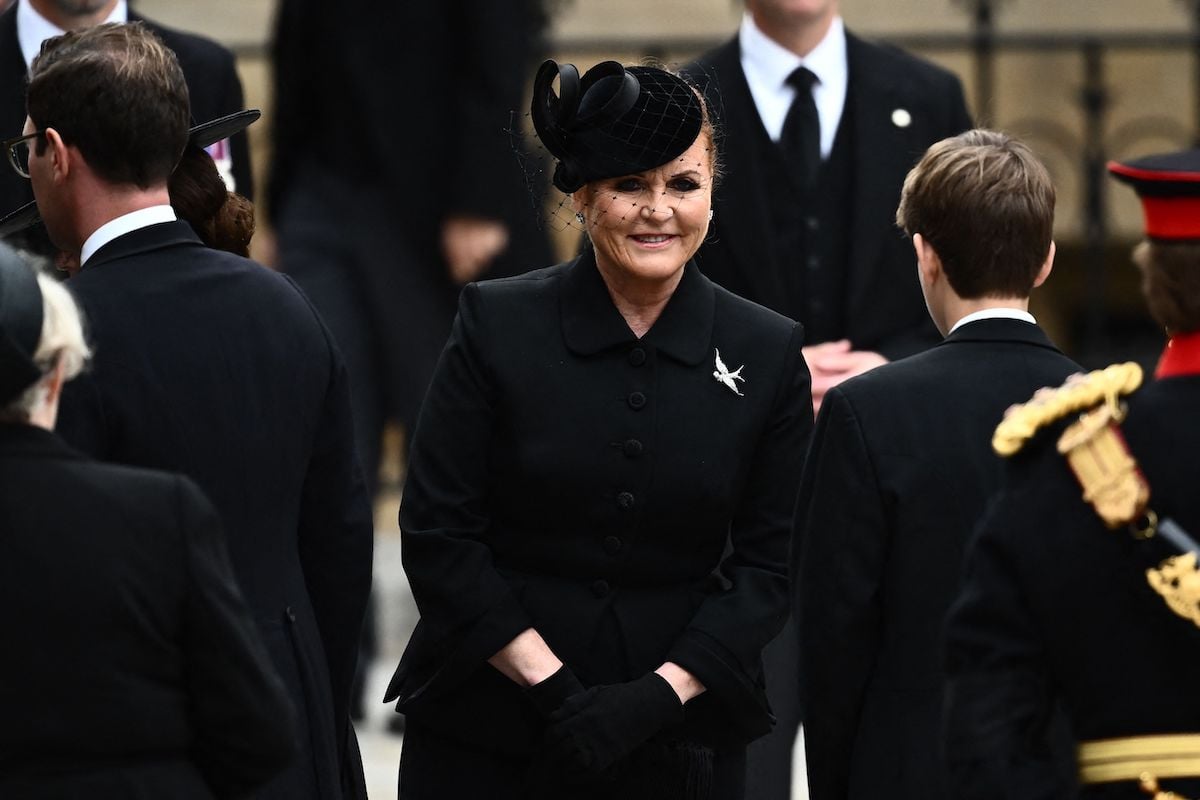 Sarah Ferguson, whose 'modest gesture' at Queen Elizabeth's funeral was refusing an invite to walk in front of Princess Beatrice and Princess Eugenie, according to body language expert Judi James, smiles as she wears all black outside Westminster Abbey for Queen Elizabeth's funeral