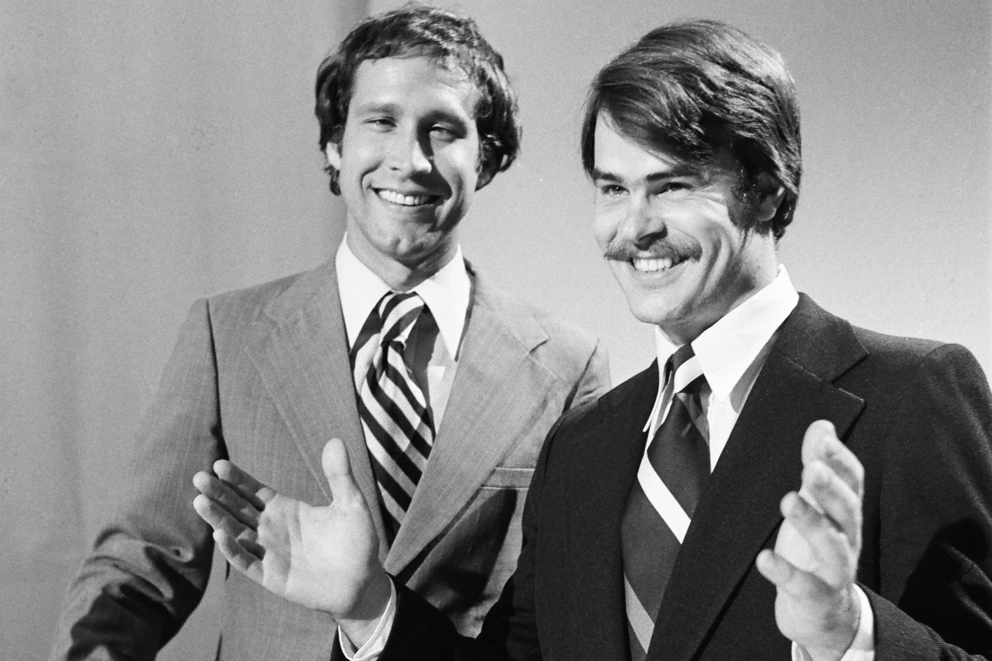 'Saturday Night Live' Chevy Chase as Gerald Ford and Dan Aykroyd as Jimmy Carter. Black-and-white photo of Chase smiling at the camera wearing a suit and tie. Aykroyd also wearing a suit and tie with his hands up in the air, looking to the side.