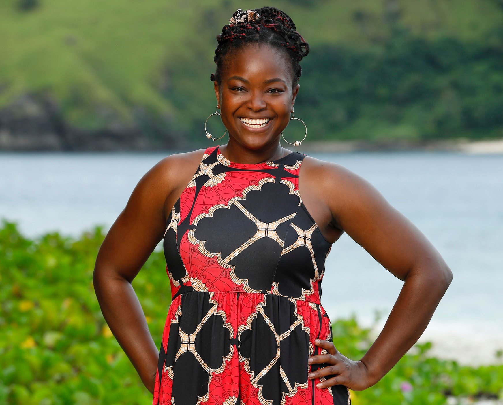 Nneka Ejere poses in a red and black dress on the beach for 'Survivor' Season 43.