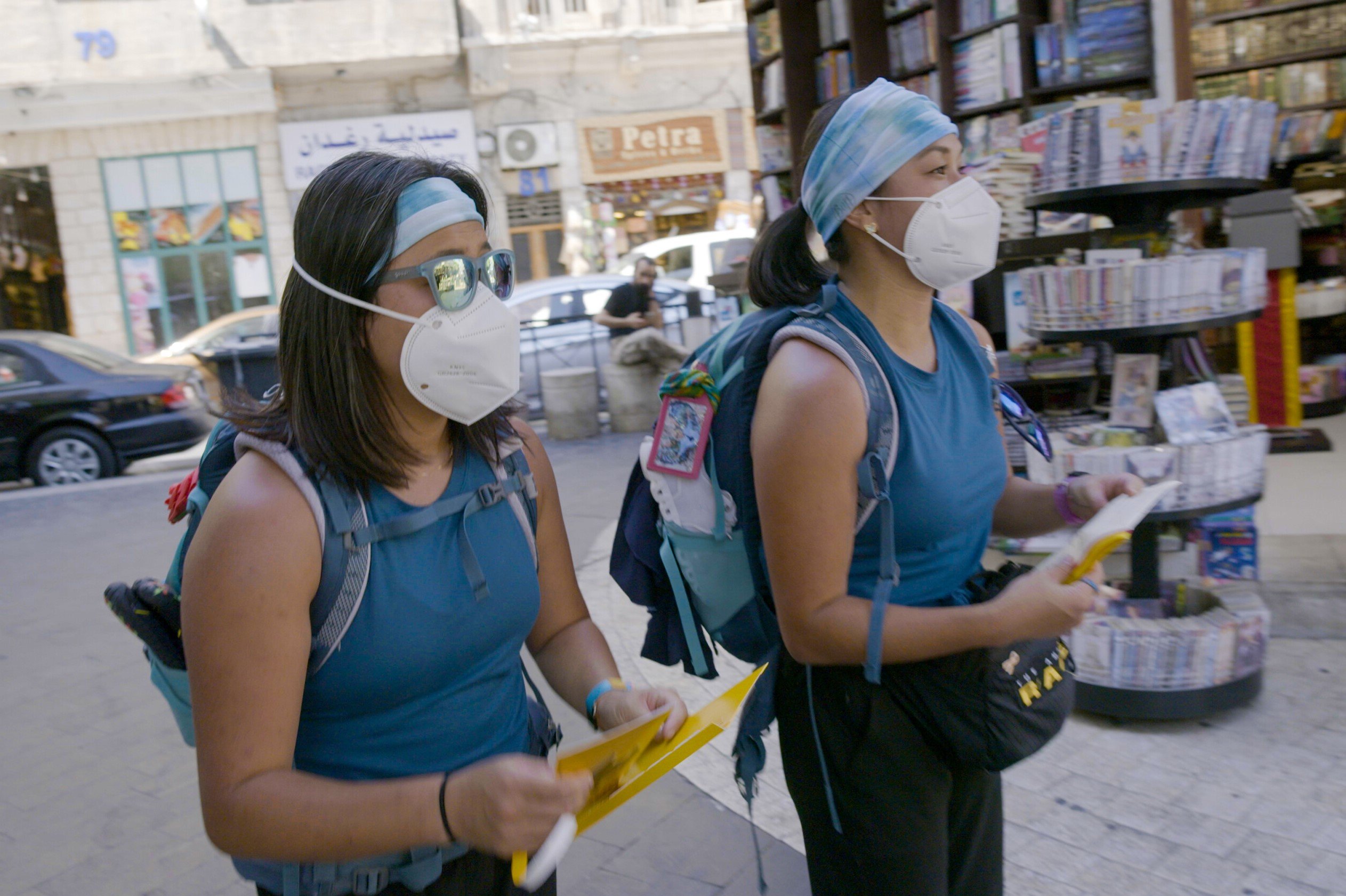 Emily Bushnell and Molly Sinert, who star in 'The Amazing Race 34' Episode 6, 'Step by Step,' wear matching teal tank tops, blue and white headbands, black pants, and white face masks.
