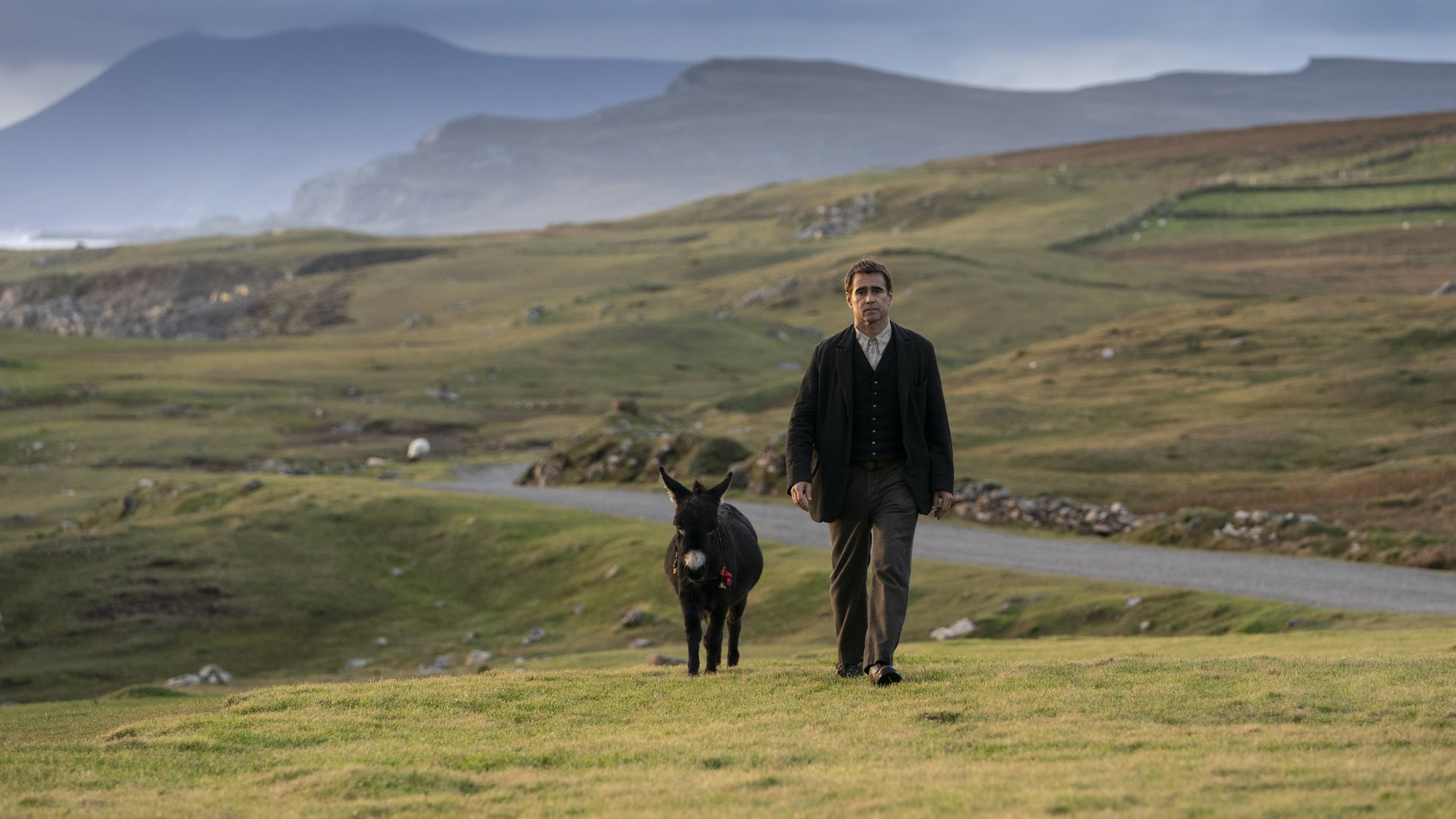 'The Banshees of Inisherin' Colin Farrell as Pádraic Súilleabháin walking alongside a donkey in a green field