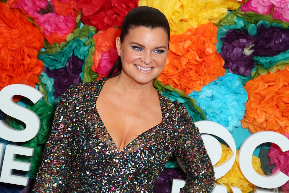 'The Bold and the Beautiful' star Heather Tom in a sparkly dress stands in front of a floral hedge.