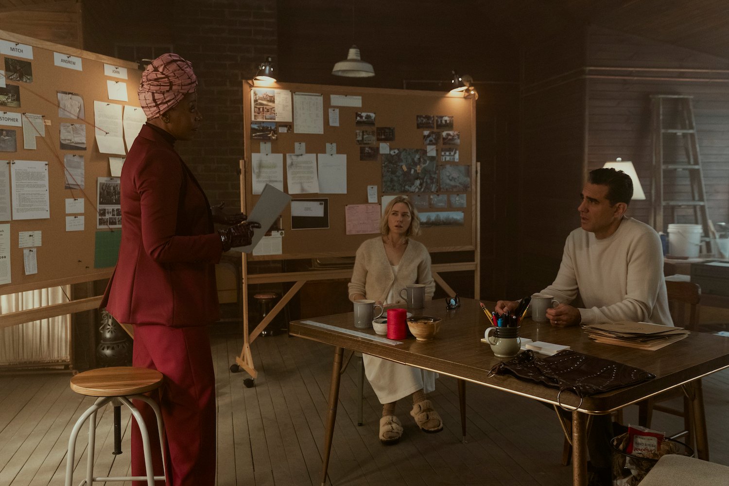 Naomi Watts and Bobby Cannavale play Dean and Nora Brannock in 'The Watcher' are seen here sitting at a table as Noma Dumezweni speaks in a production still. They're characters are based on the Broaddus family.
