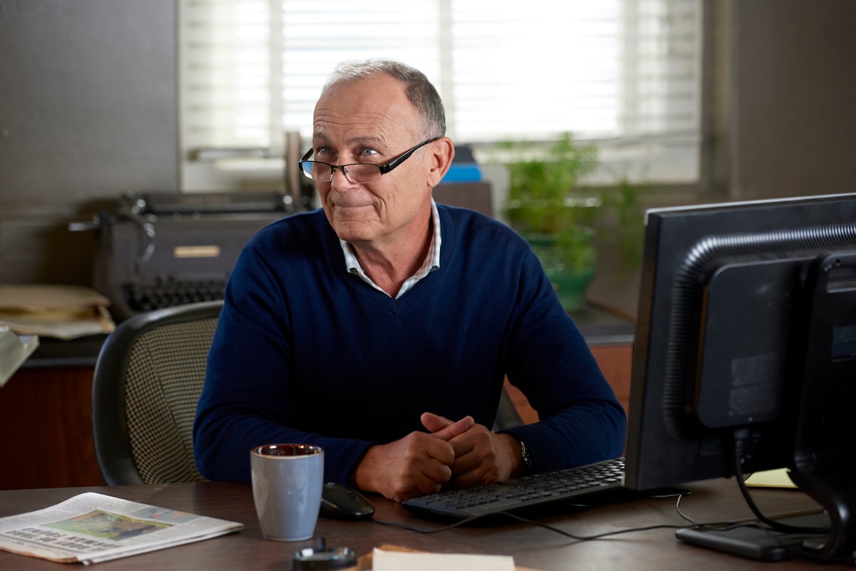 Michael Kopsa sitting at a desk in the Hallmark movie 'Chronicle Mysteries: The Wrong Man'