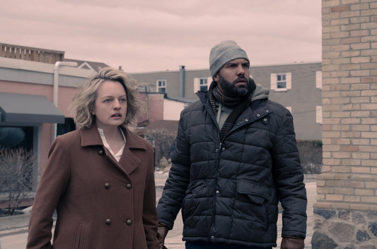 Elisabeth Moss as June and O-T Fagbenle as Luke in The Handmaid's Tale. June and Luke stand outside the Gilead Information Center in Canada.