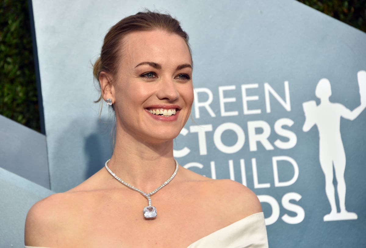 Yvonne Strahovski plays Serena Joy Waterford in The Handmaid's Tale Season 5. Stahovski wears a white dress and silver necklace and earrings. 