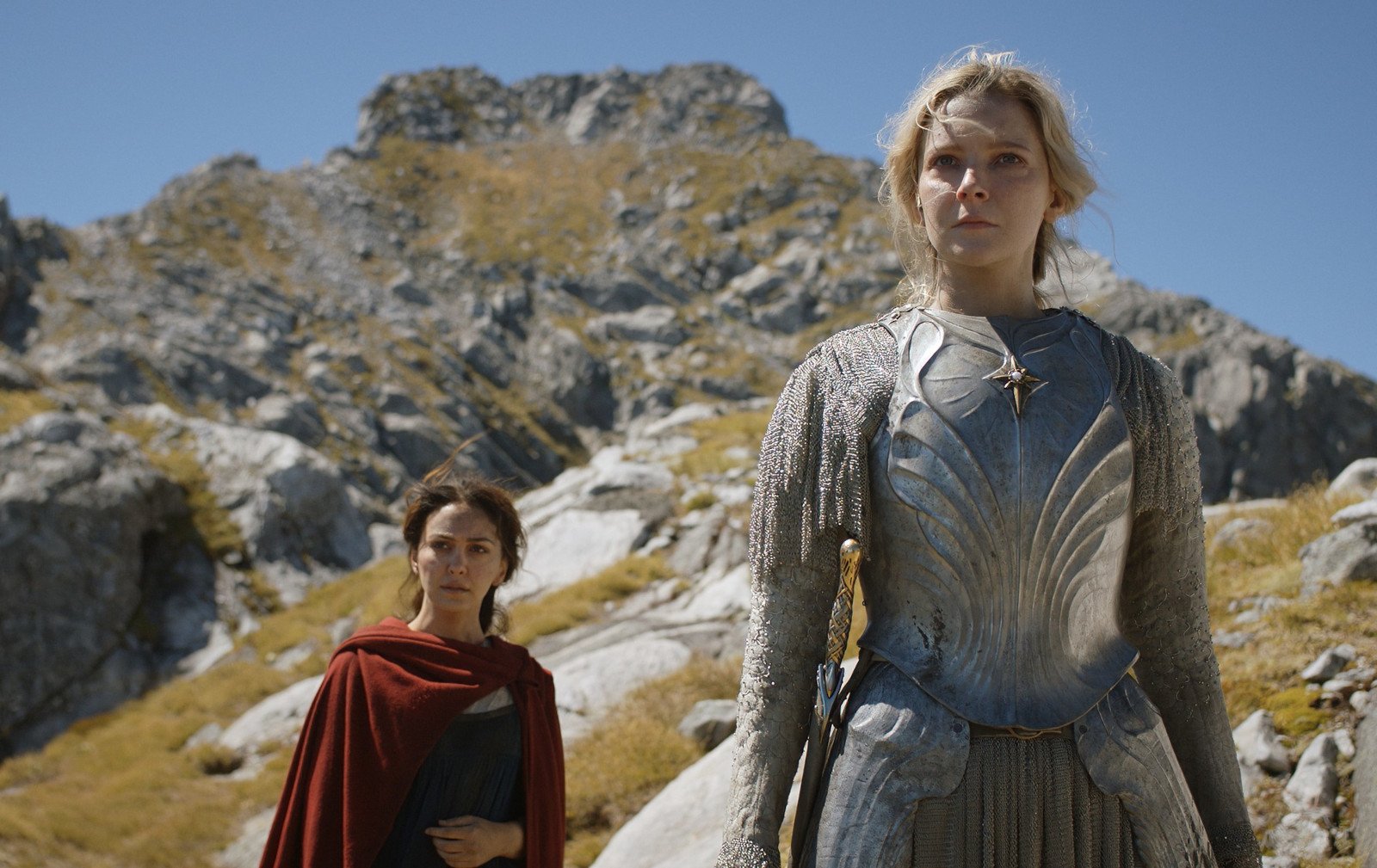 Nazanin Boniadi and Morfydd Clark in 'The Rings of Power' Episode 7 for our article about Easter Eggs. They're standing side by side on a mountain and look concerned.