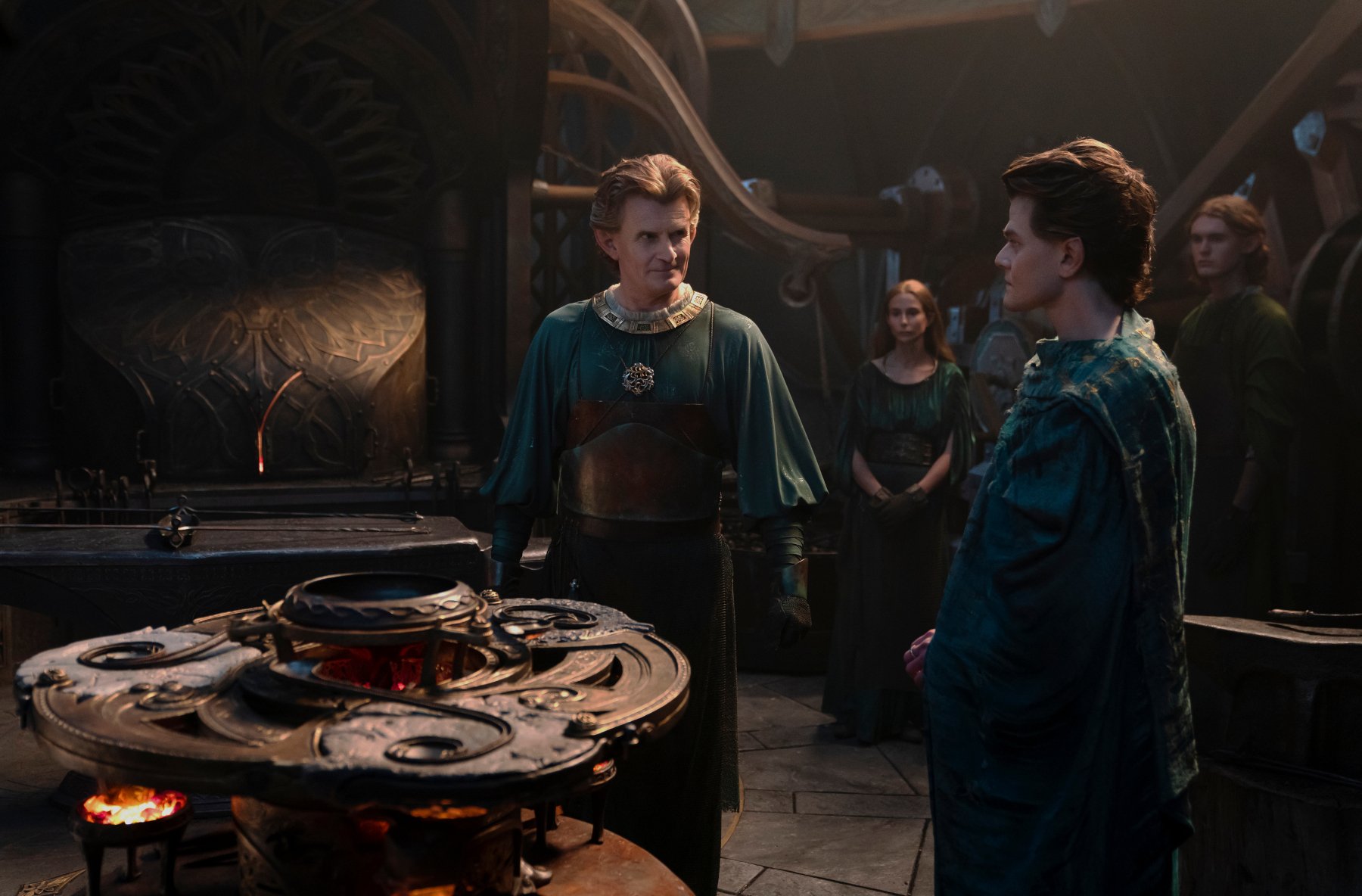 Charles Edwards and Robert Aramayo as Celebrimbor and Elrond in 'The Rings of Power' for our article about the new character appearing in season 2. They're standing next to one another in front of a forge.