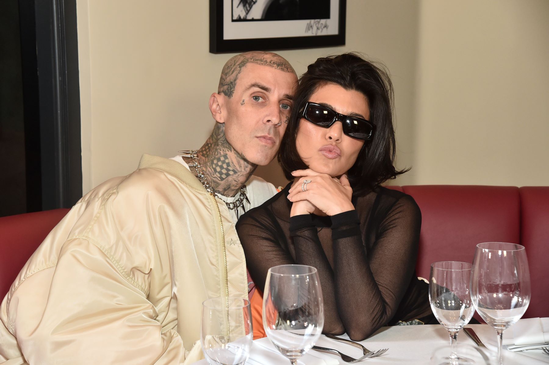 Travis Barker and Kourtney Kardashian posing for paparazzi at the ribbon cutting ceremony for Crossroads Kitchen