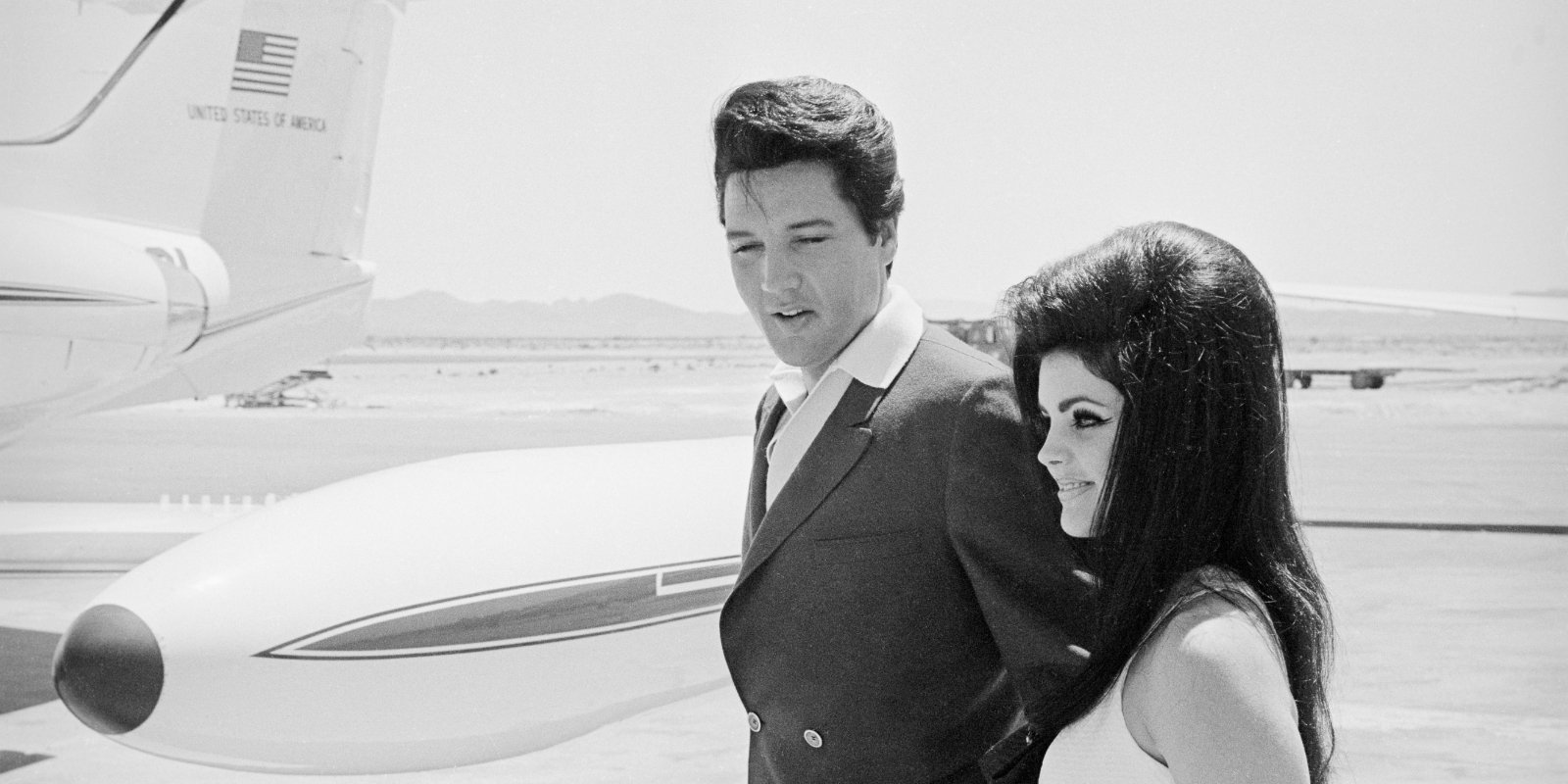 Elvis and Priscilla Presley photographed approaching an airplane.