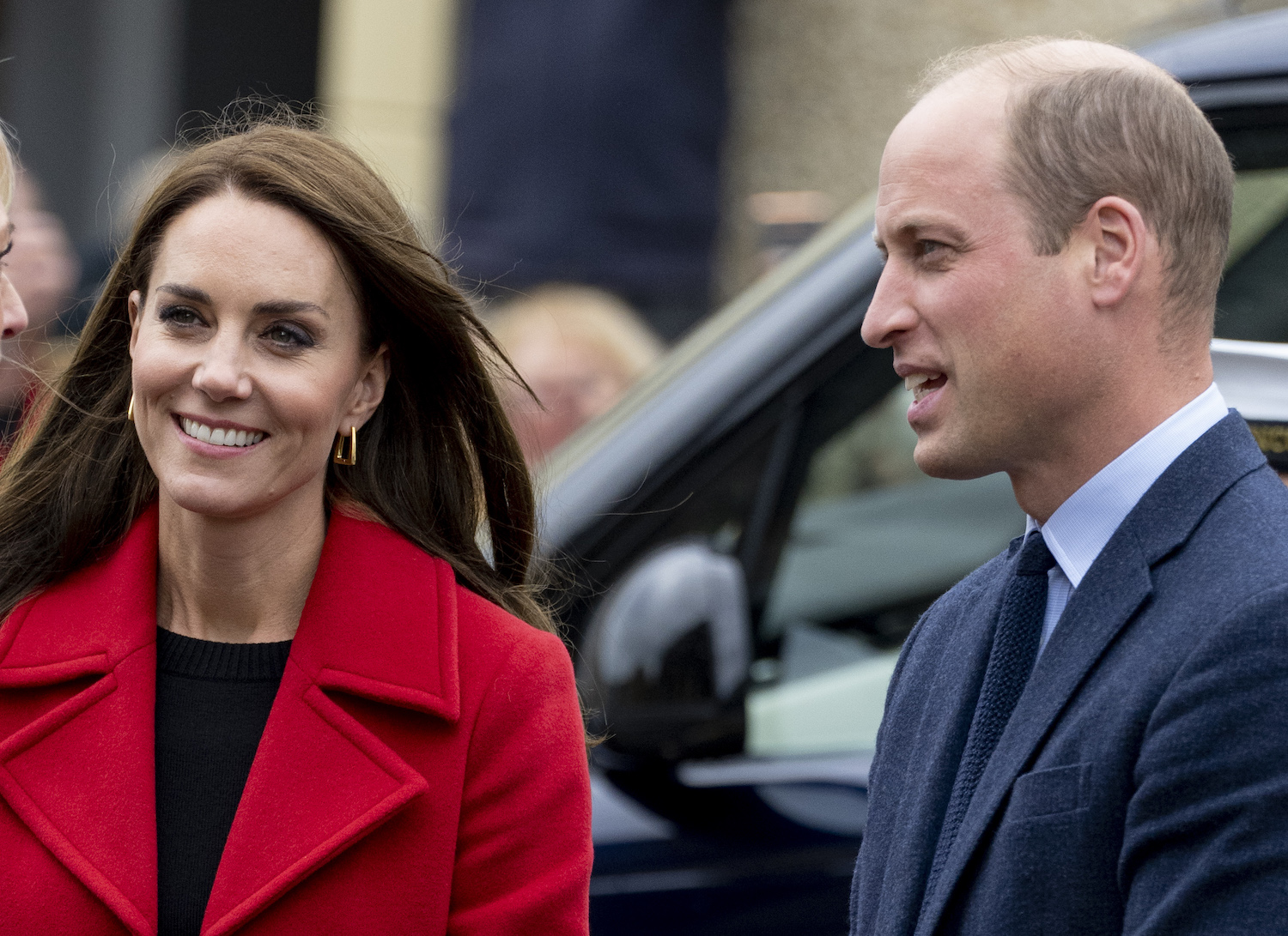 Kate Middleton wears a red coat and Prince William wears a suit and toes with the couple's body language revealing confidence