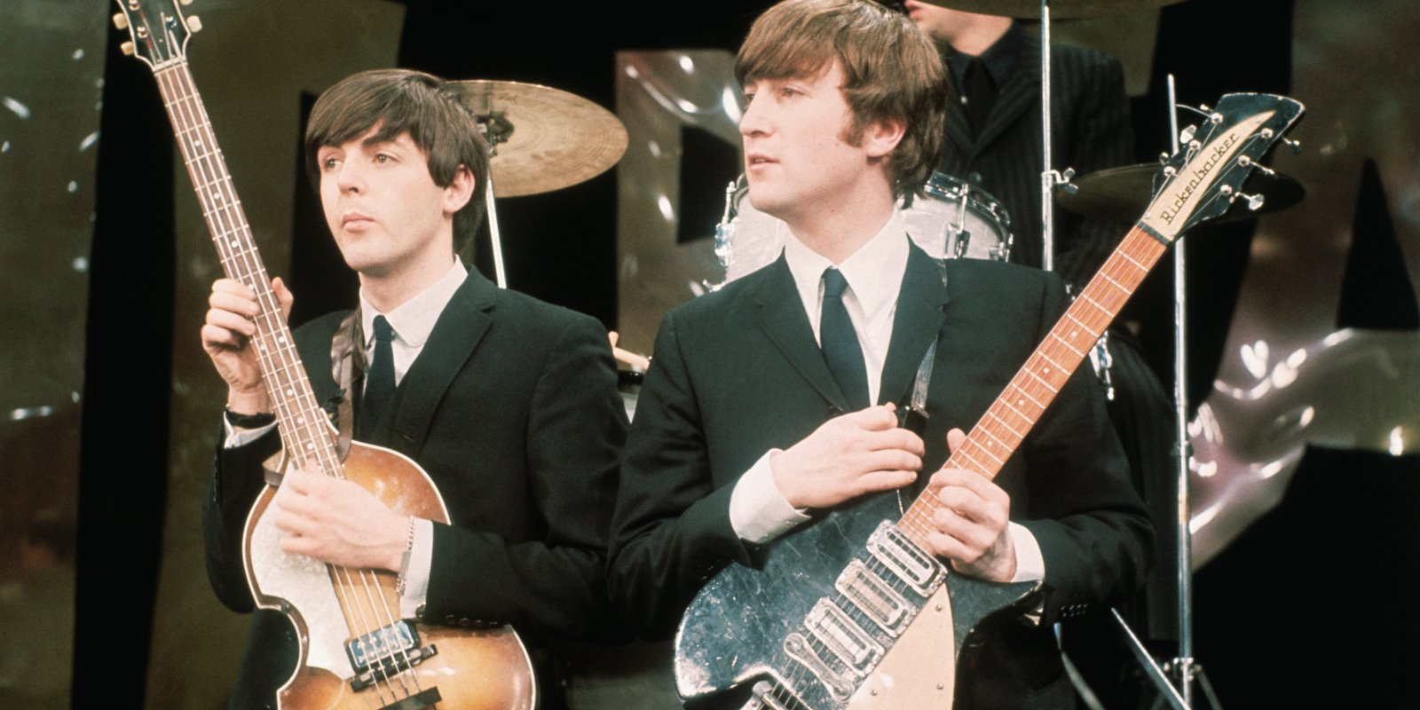 Paul McCartney and John Lennon pose together on stage with the members of The Beatles.