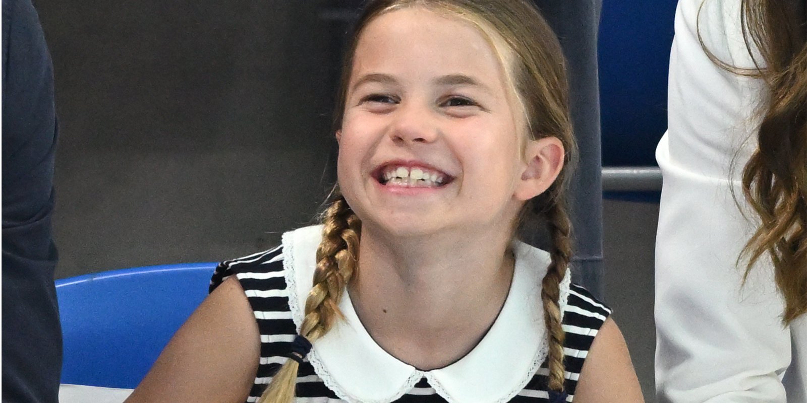 Princess Charlotte wears a stiped dress with a peter pan collar as she smiles for the cameras.