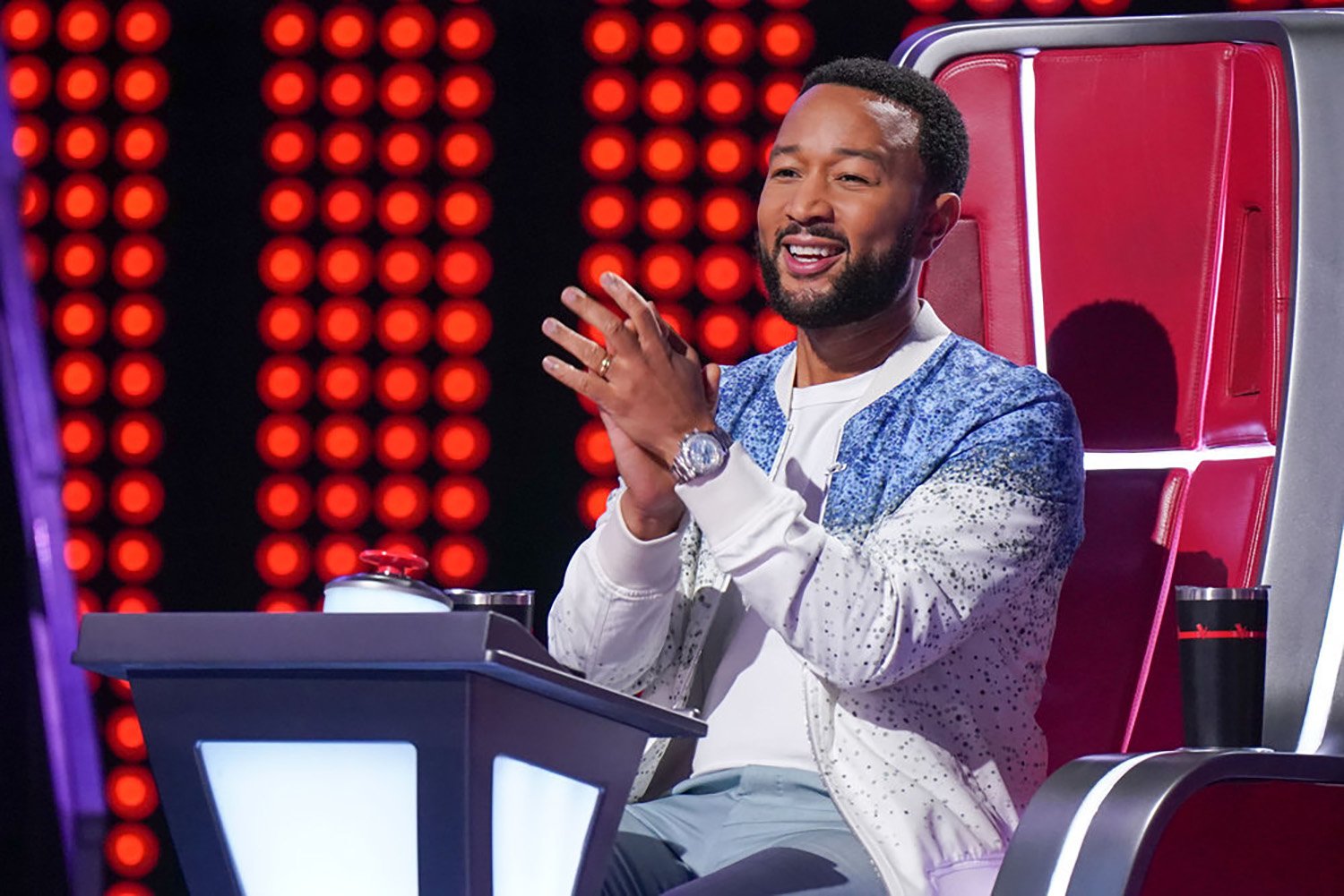 John Legend claps his hands and smiles in his seat on The Voice Season 22