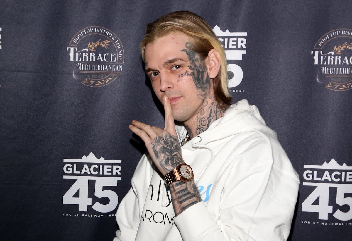 Aaron Carter, whose tell-all book has been delayed after his death, poses with one finger over his lips at an event.