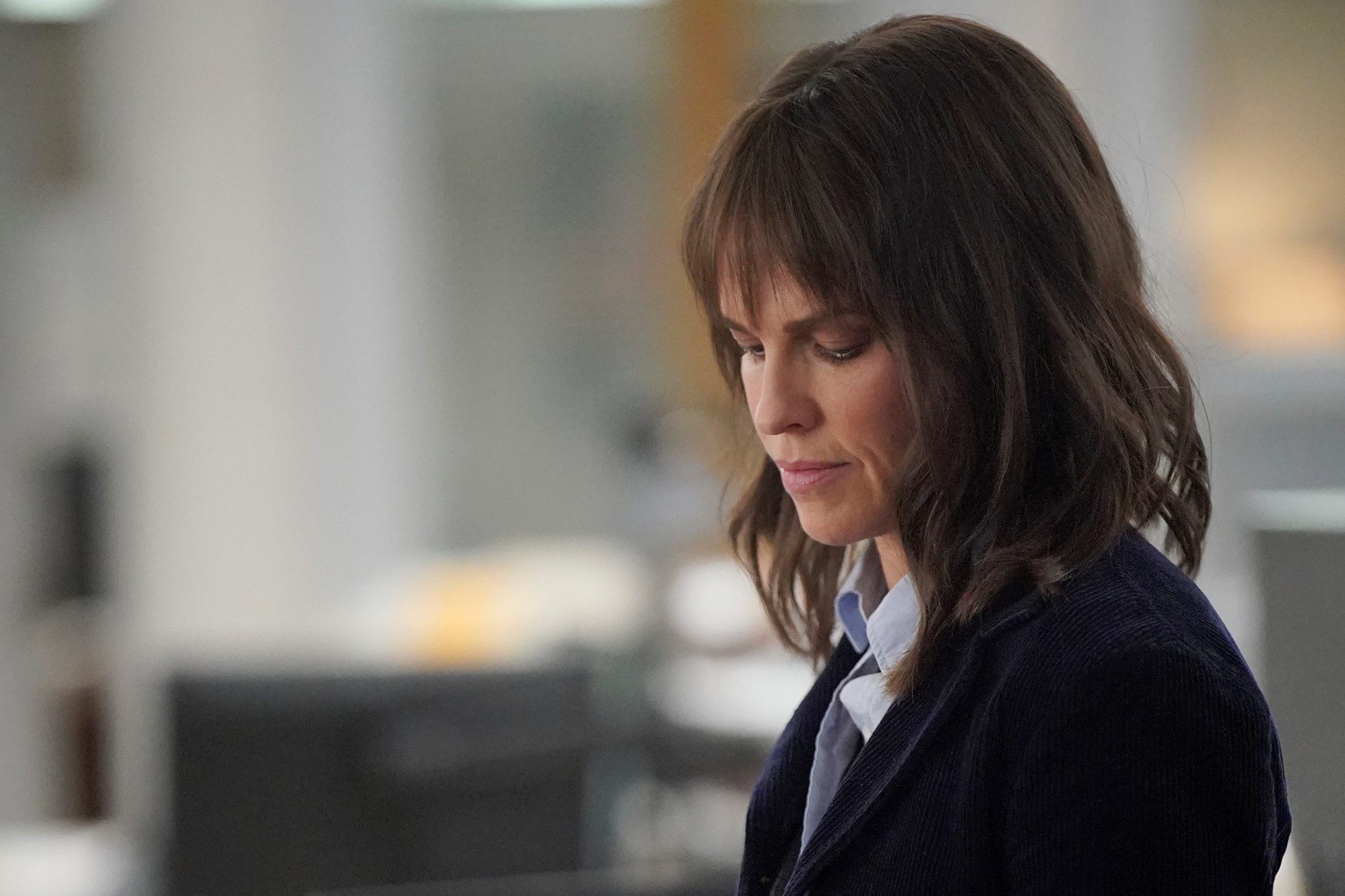 Hilary Swank stars as Eileen Fitzgerald in 'Alaska Daily' Episode 6 on ABC, and wears a black coat over a light blue button-up shirt in the photo.