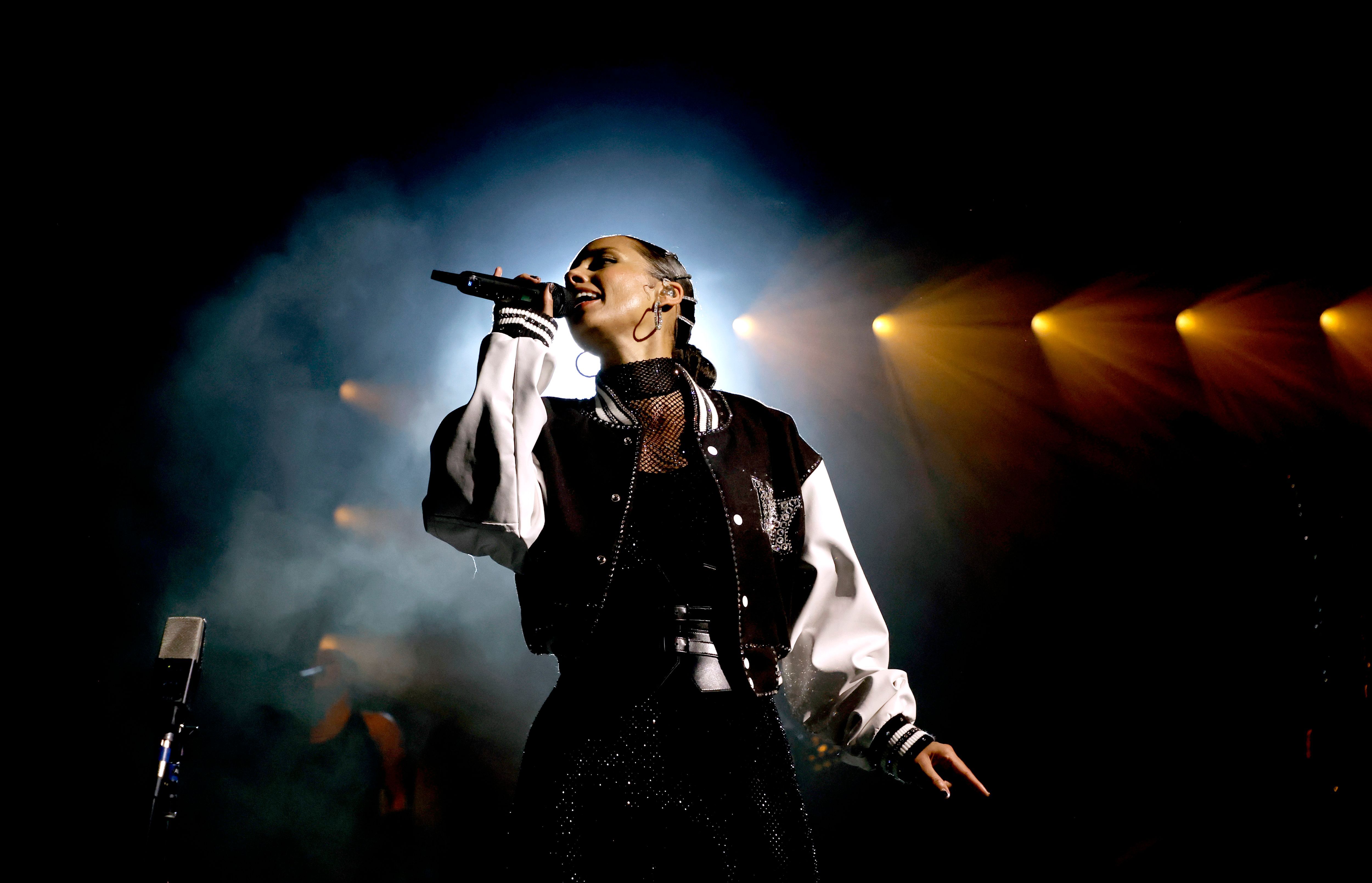 Alicia Keys sings while wearing a black-and-white lettermen jacket