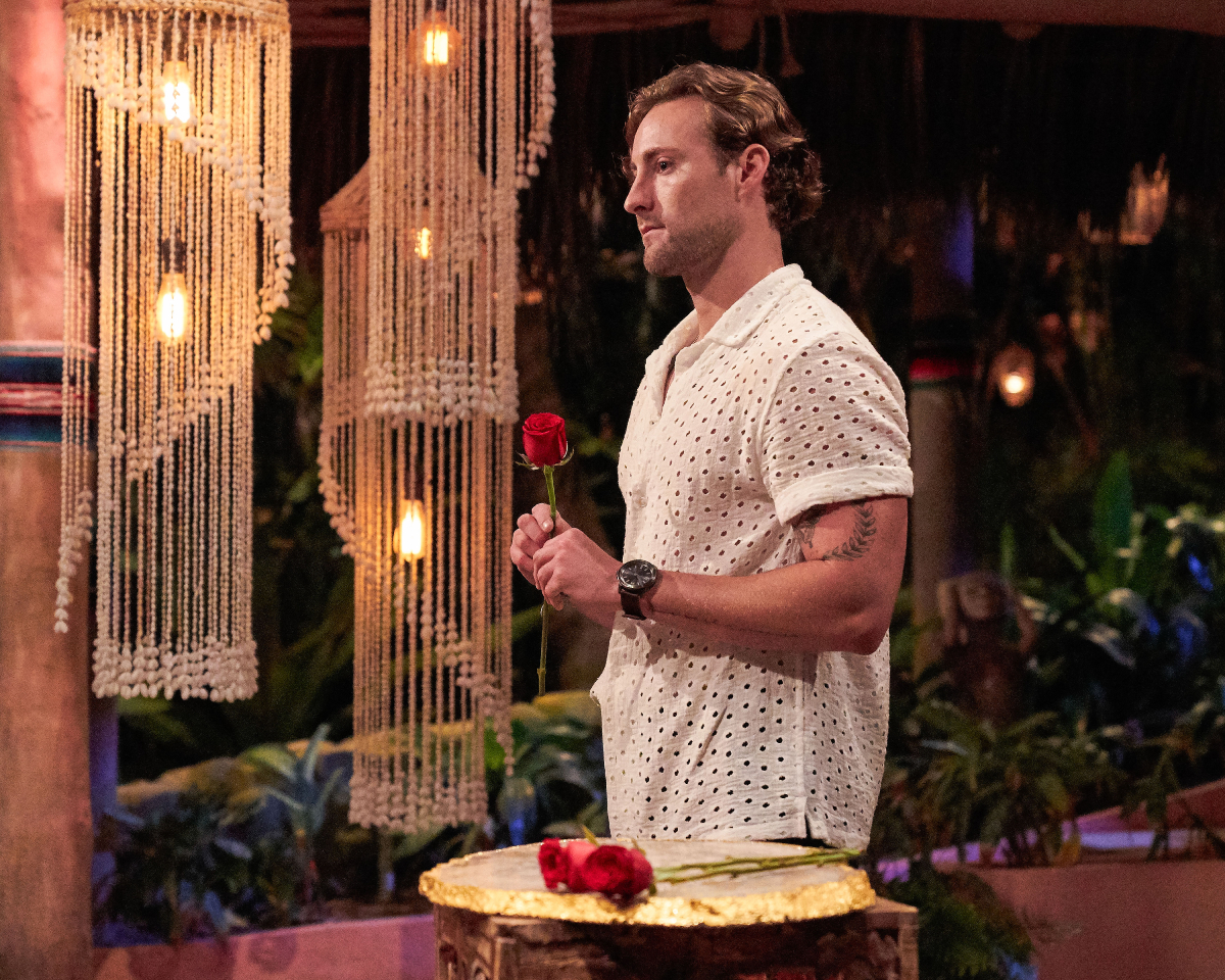 On Bachelor in Paradise 2022, Johnny DePhillipo holds a rose. He is wearing a white button-down shirt. 