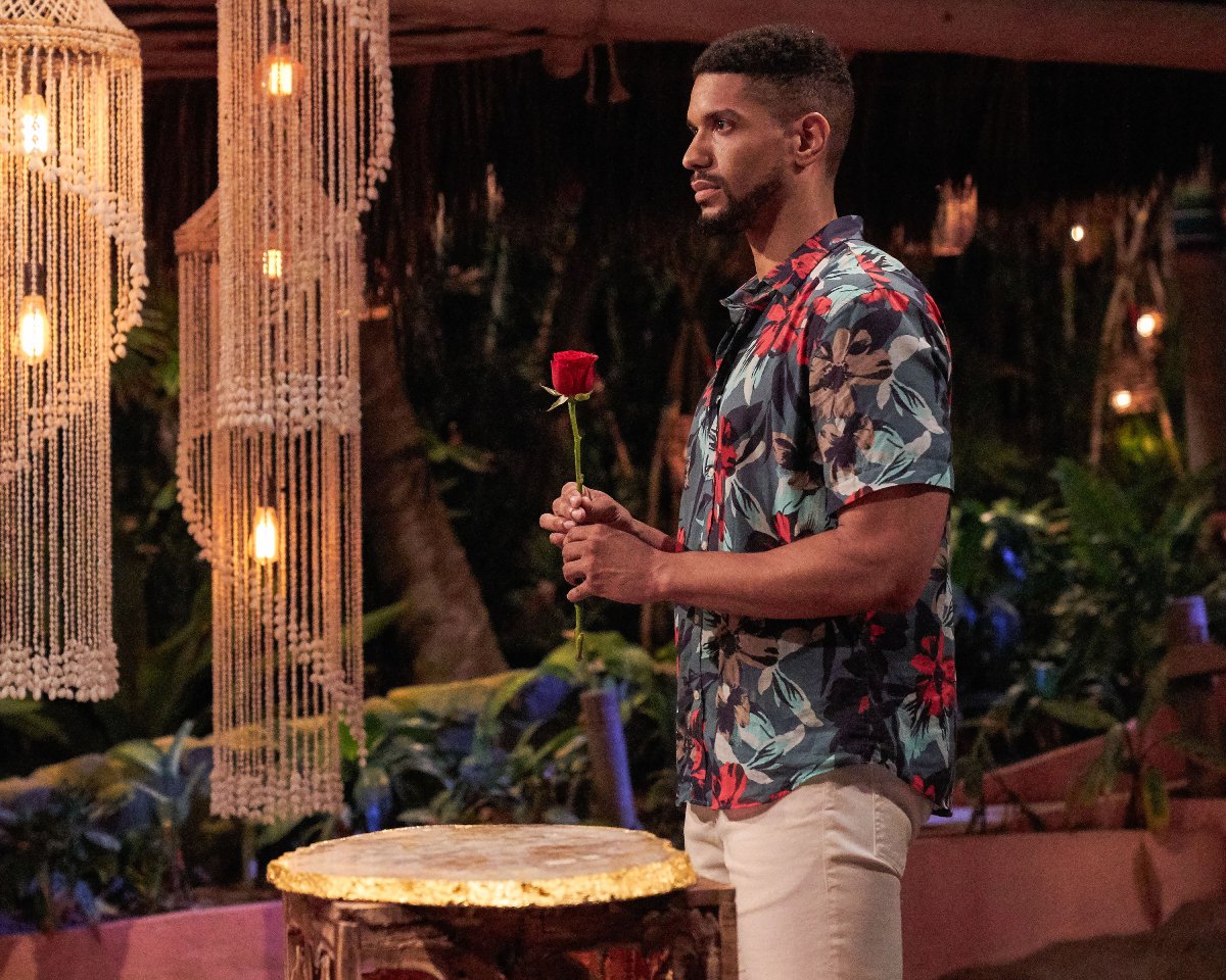 Are Romeo and Kira from Bachelor in Paradise still together? Romeo holds a rose, wearing a Hawaiian shirt and khakis.