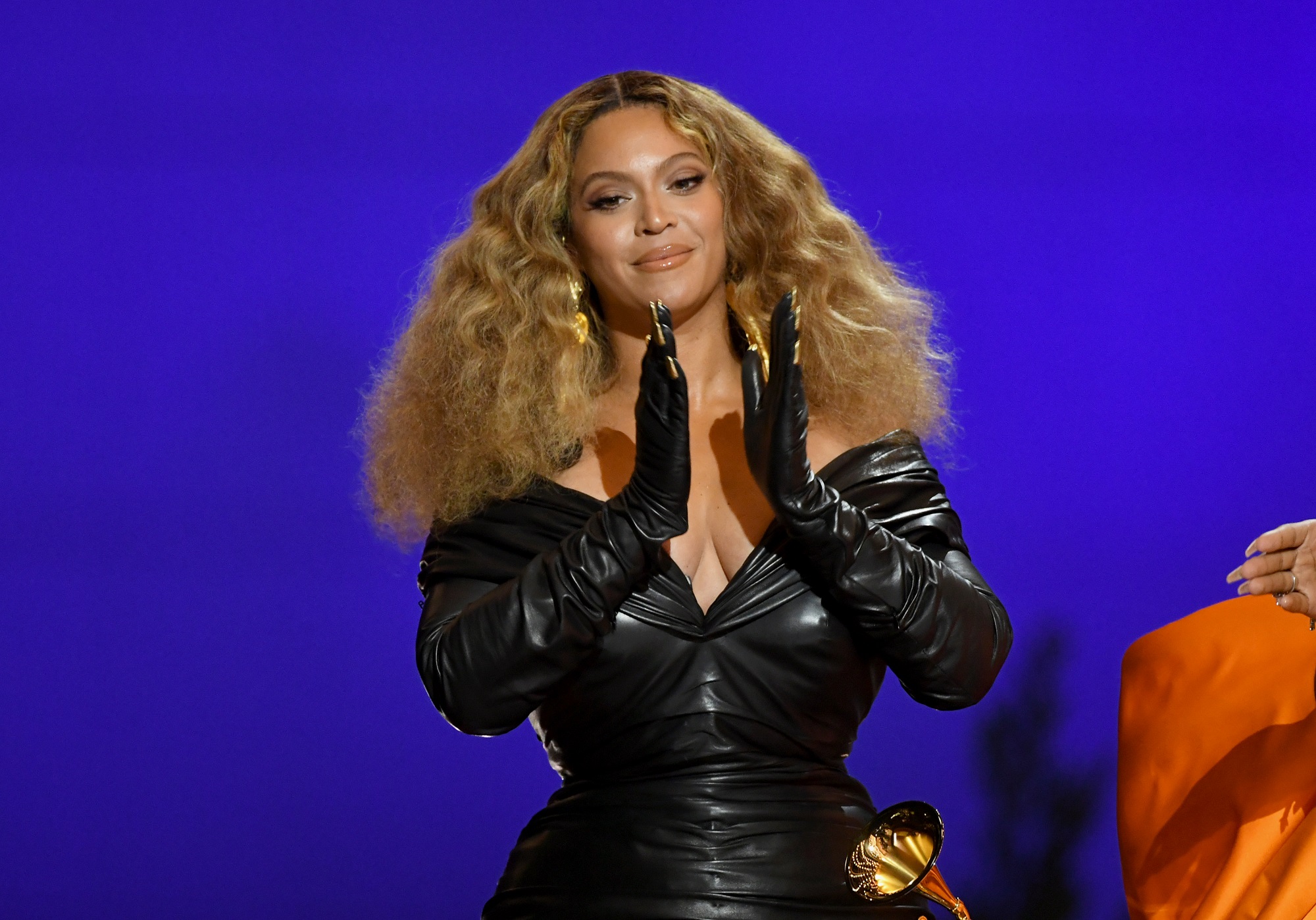 Beyoncé begins to clap while wearing a black leather dress