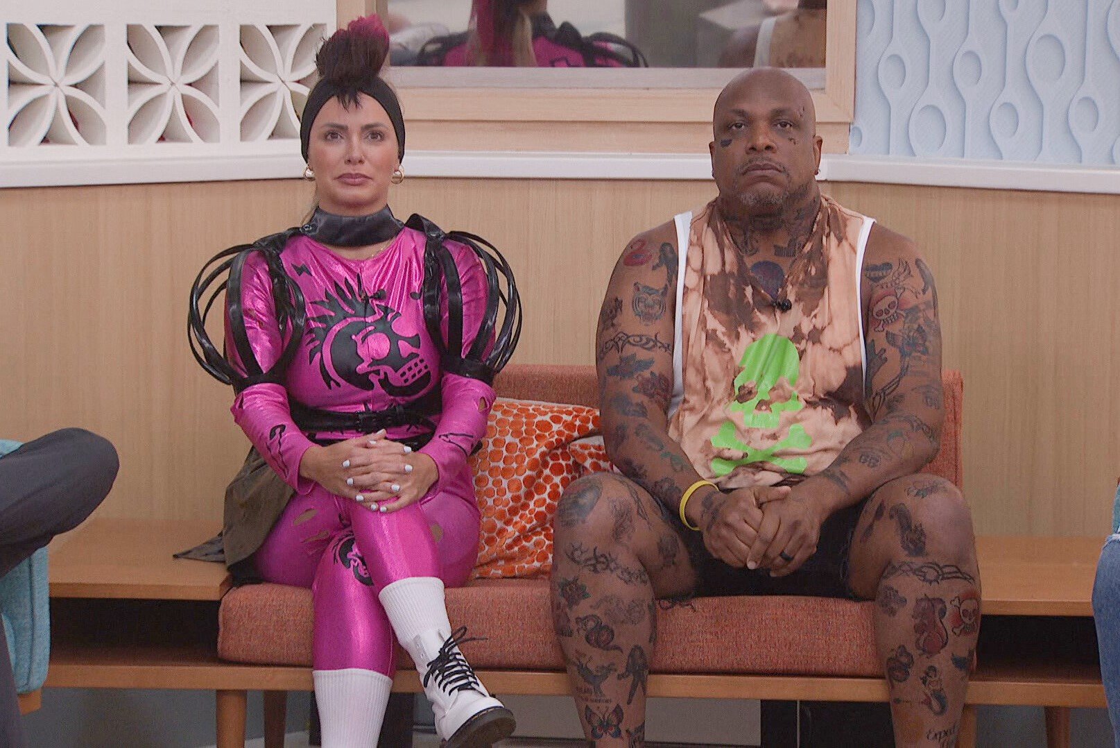Indy Santos and Terrance Higgins, who starred in 'Big Brother 24' on CBS, sit next to each other on the nomination couch. Indy wears her pink and black punk rocker unitard. Terrance wears a brown and green tie dye tank top and black shorts.