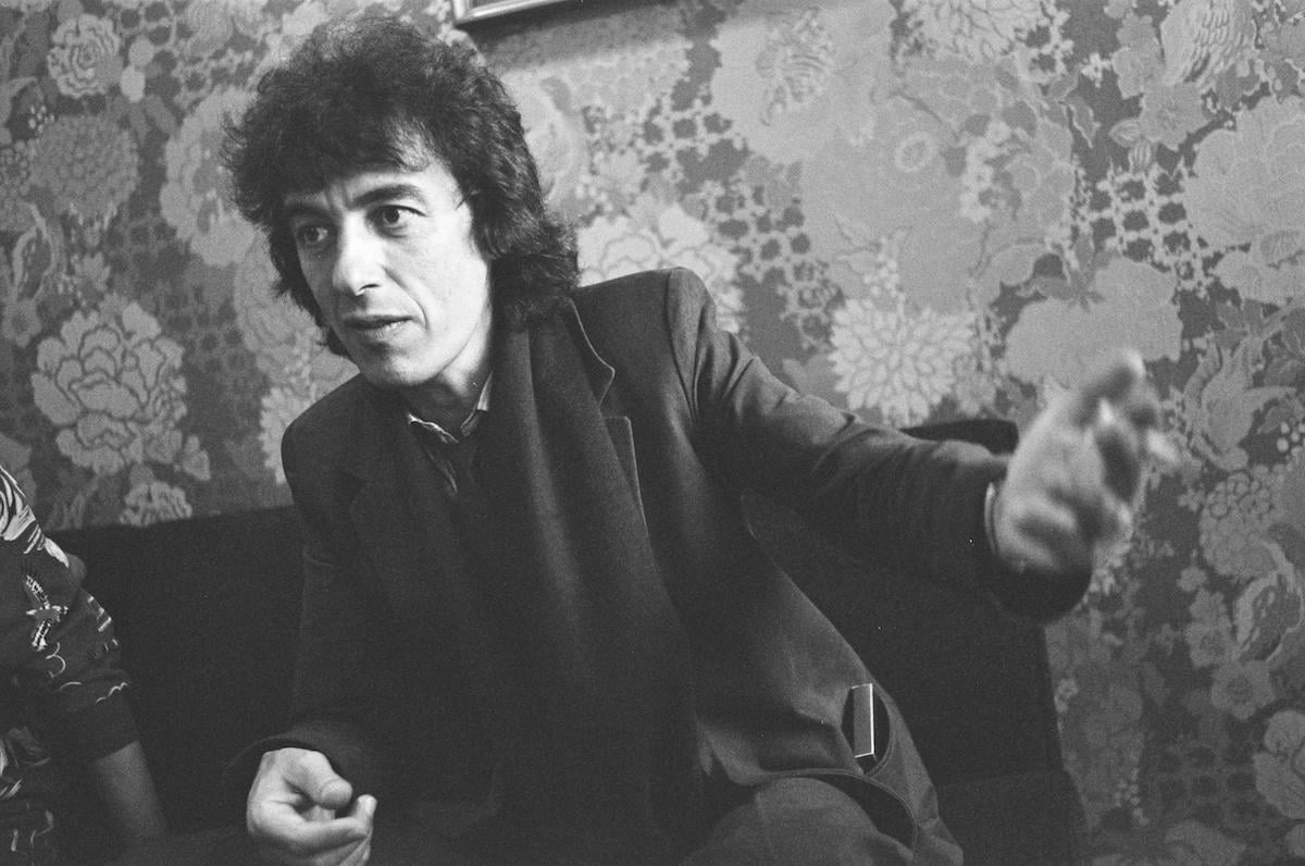 Bill Wyman in black and white, looking off camera and gesturing, in 1982