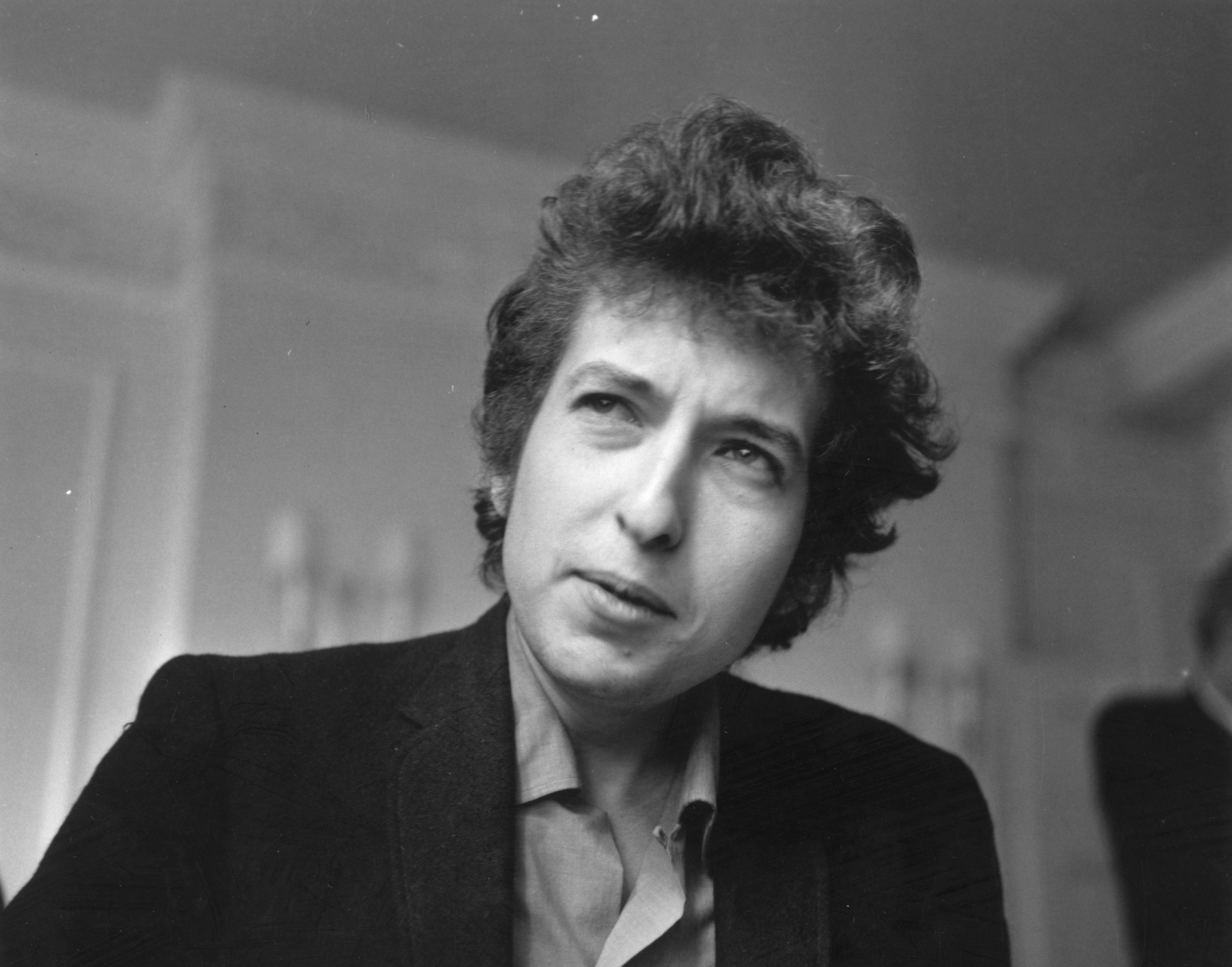 A black and white picture of Bob Dylan wearing a jacket.