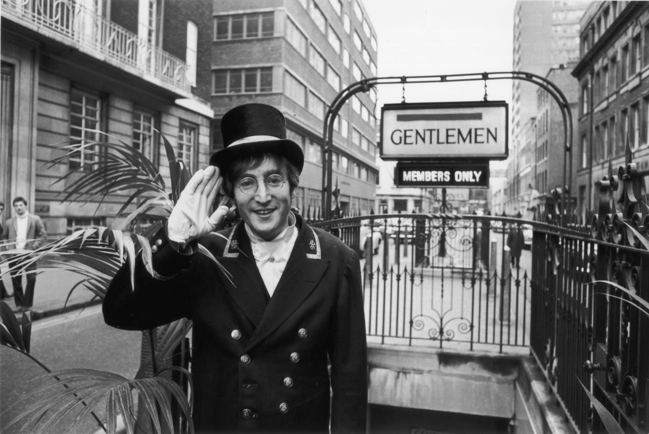 John Lennon wears a top hat and white gloves.