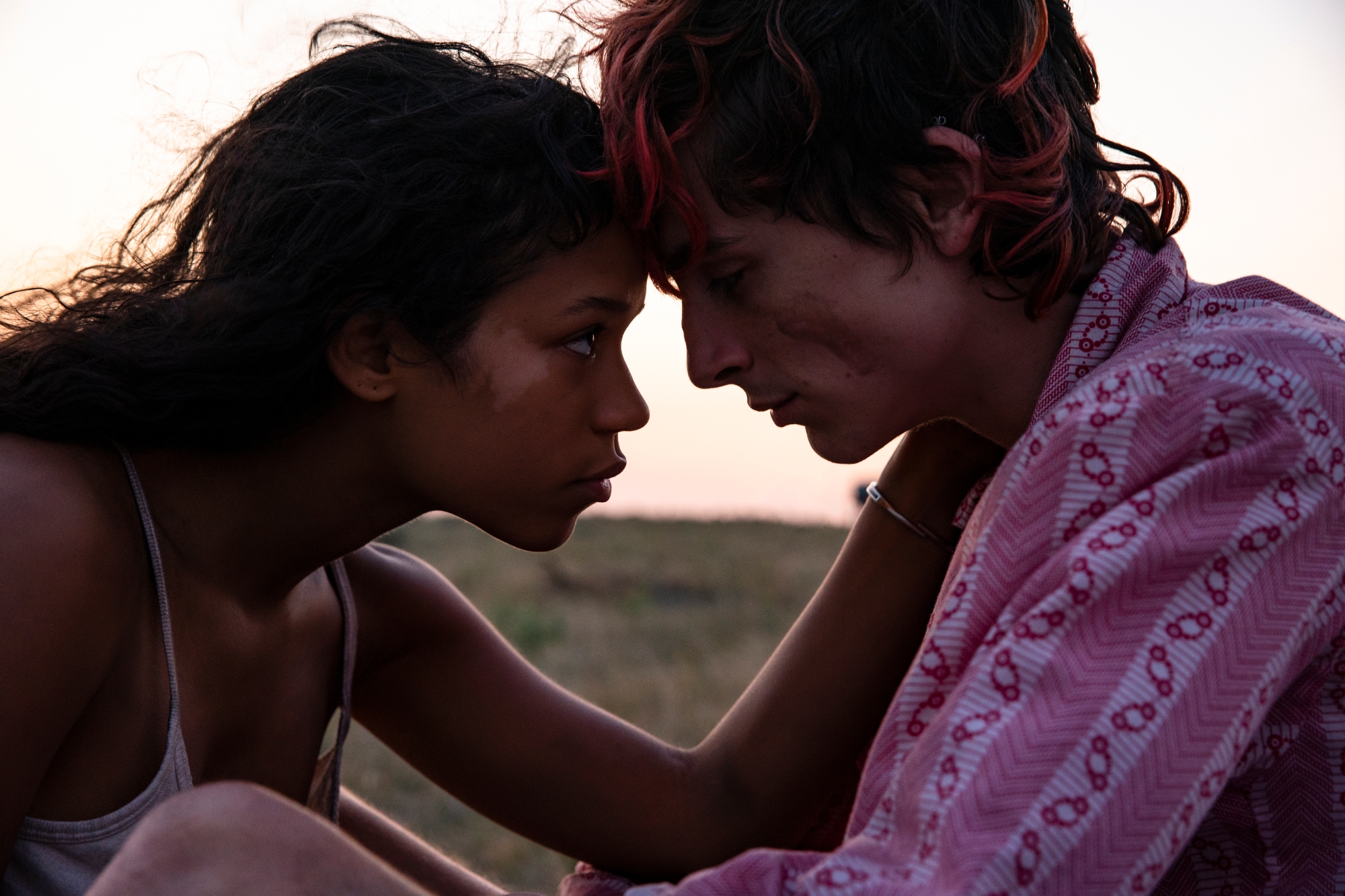 'Bones and All' Taylor Russell as Maren and Timothée Chalamet as Lee. Russell is looking into Chalamet's eyes while she rests her hand on his cheek.