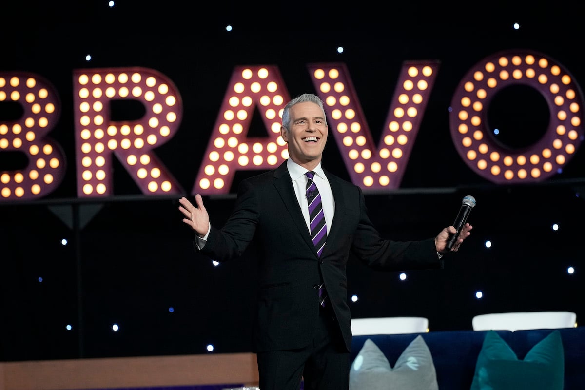 'Bravo' star Andy Cohen on a stage in front of a lit 'Bravo' logo
