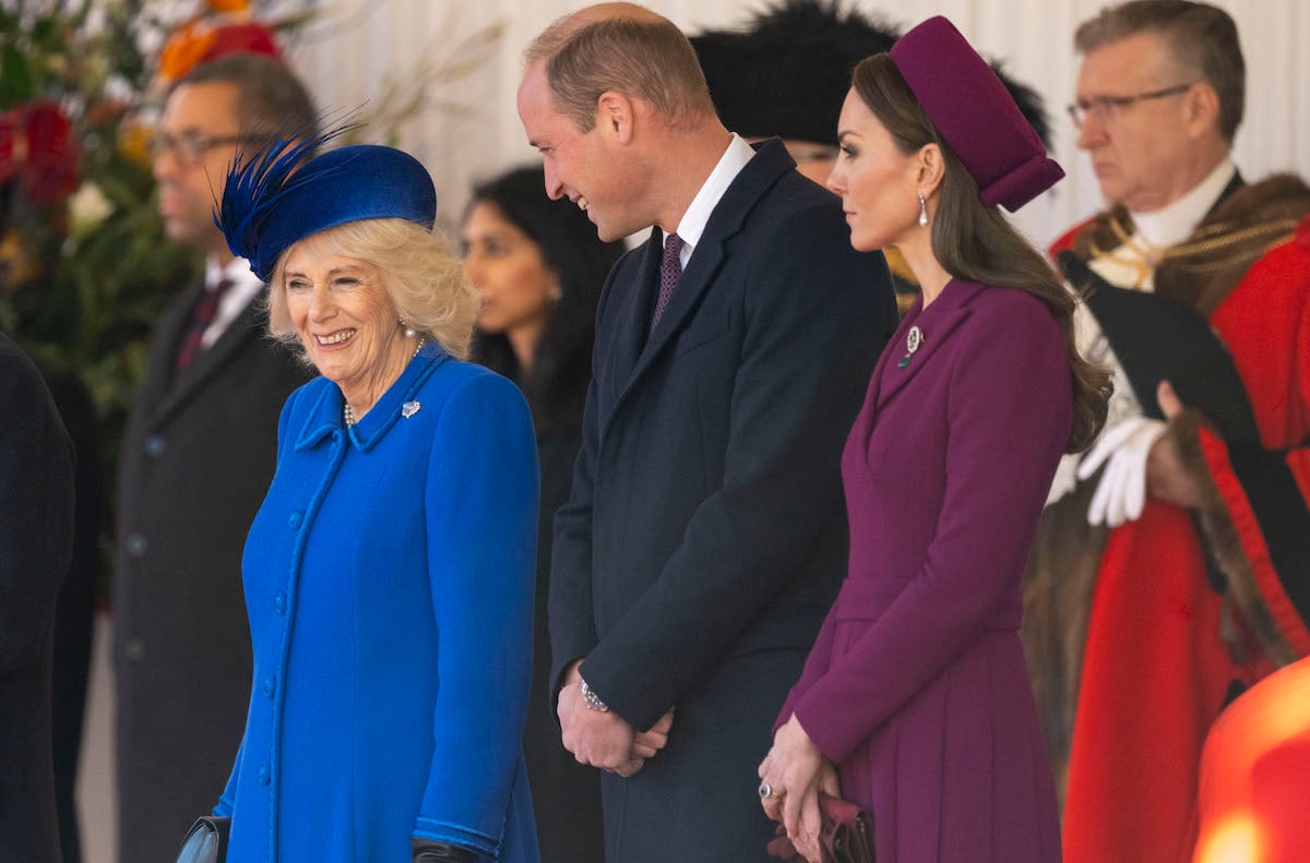 Camilla Parker Bowles, who a body language expert said exhibited a 'small gesture of anxiety' as Prince William and Kate Middleton approached during a welcome ceremony for a Nov. 22 state visit, smiles standing next to Prince William, and Kate Middleton