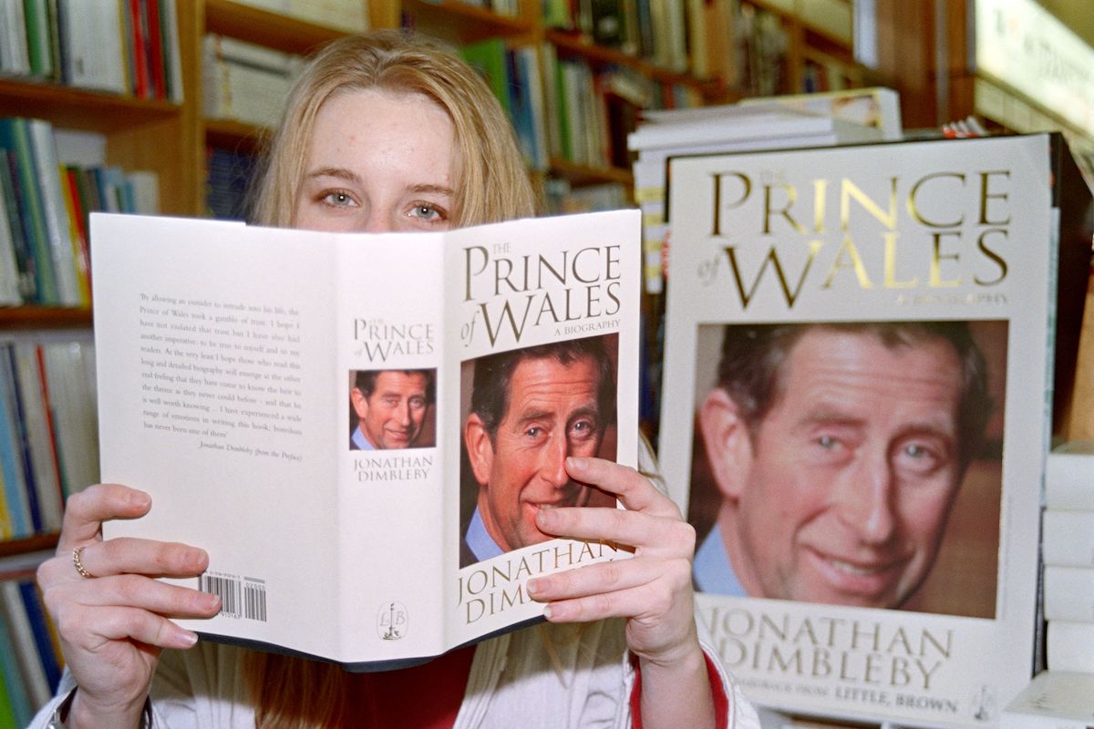 Caroline Norman holds up a copy of Jonathan Dimbleby's King Charles III biography, 'The Prince of Wales,' which according to Kitty Kelley depicted Princess Diana as a 'hired womb' 