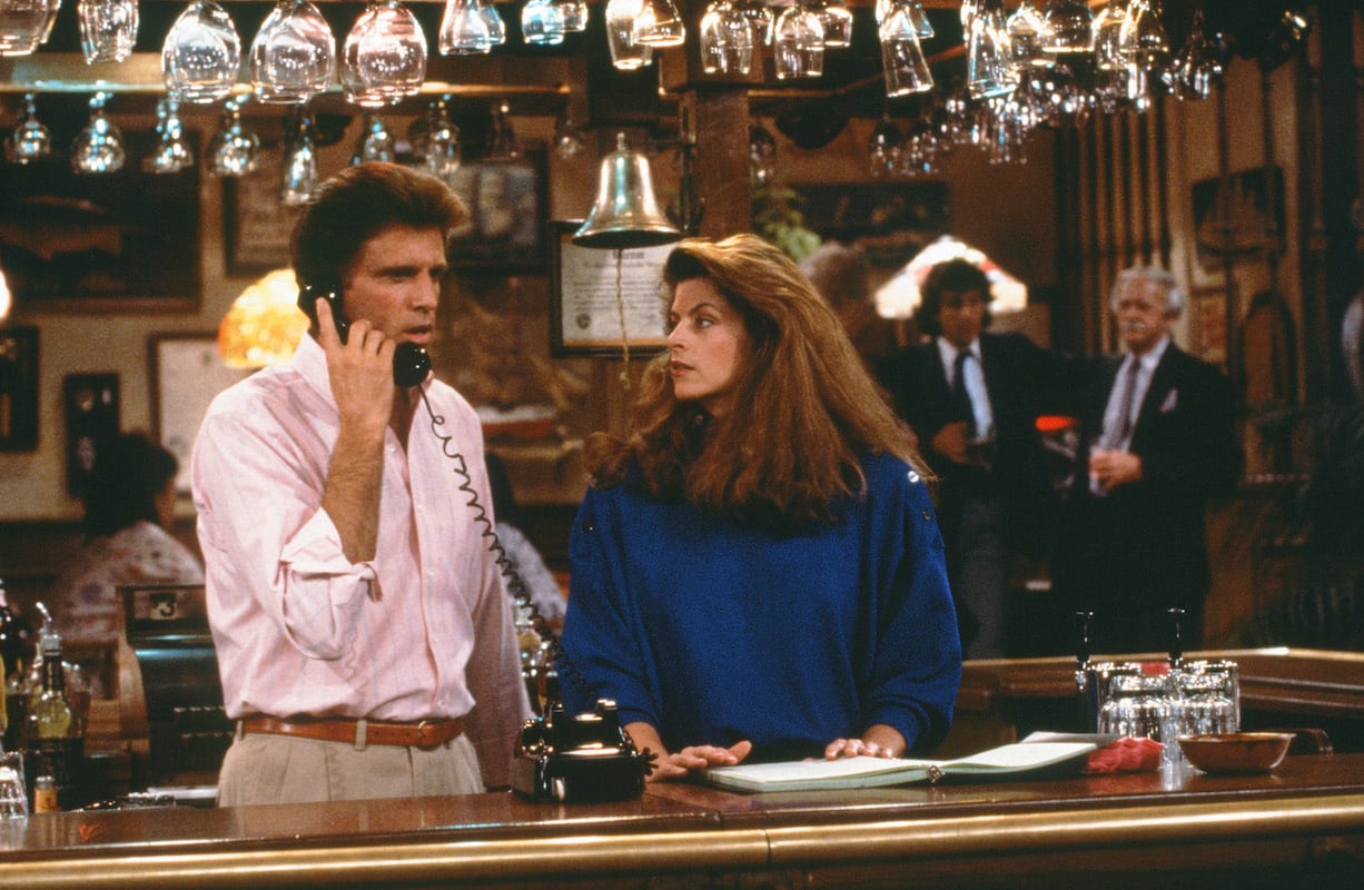 'Cheers': Kirstie Alley looks at Ted Danson who is on the phone behind the bar