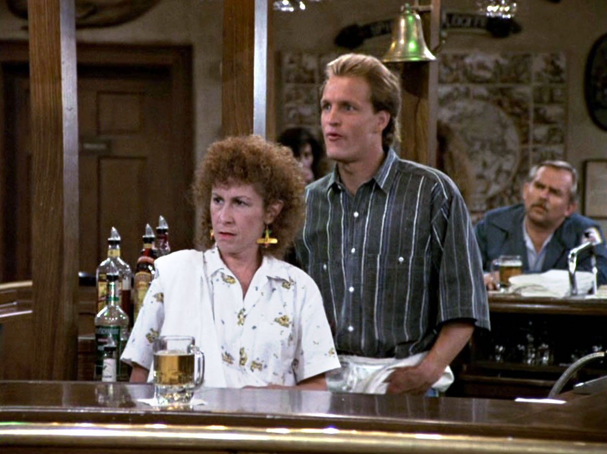 'Cheers': Carla (Rhea Perlman) and Woody (Woody Harrelson) stand behind the bar while Cliff (John Ratzenberger) sits on his stool