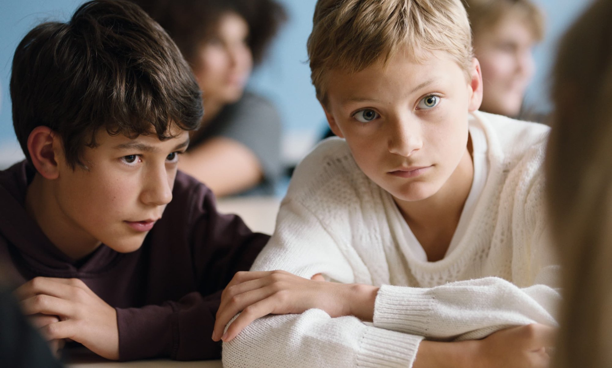 'Close' Gustav De Waele as Rémi and Eden Dambrine as Léo with their arms crossed on a table sitting next to each other.