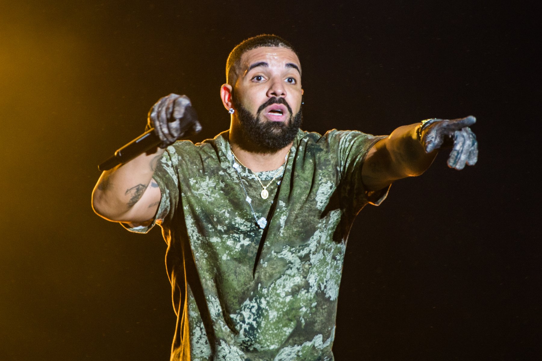 Drake, who shared the top 2 spots on the Billboard Hot 100 with Taylor Swift, wearing a green shirt on stage