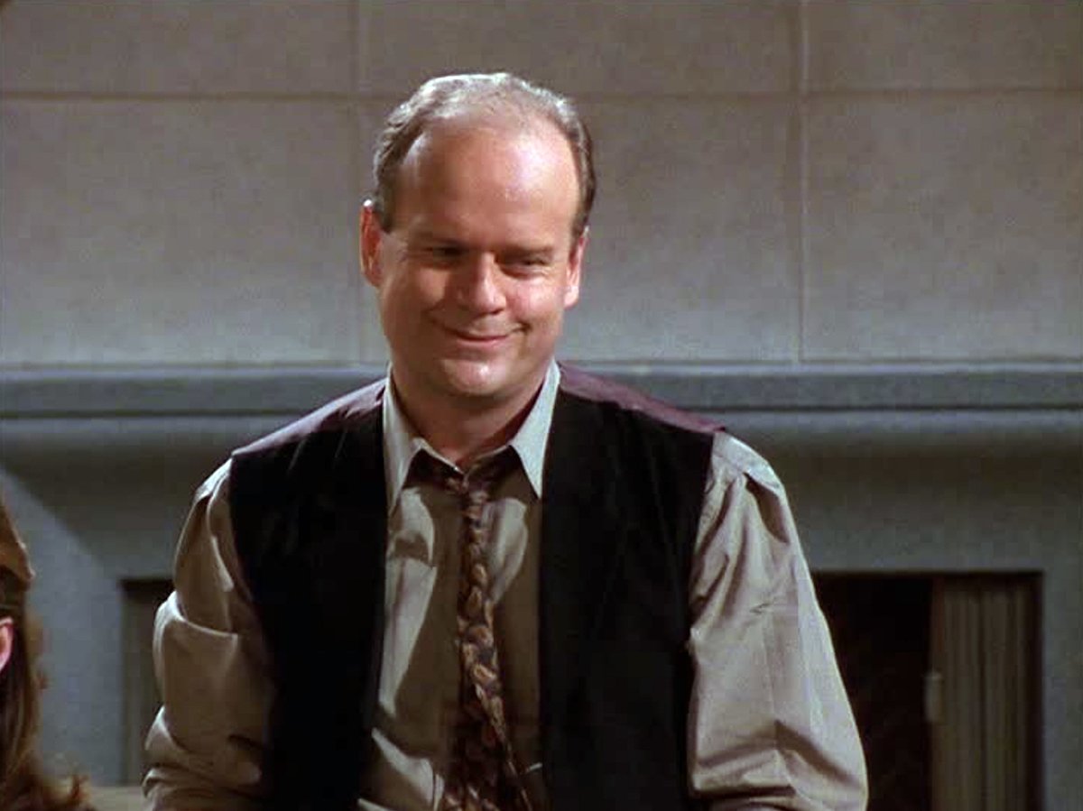 Frasier Crane (Kelsey Grammer) smiles sheepishly