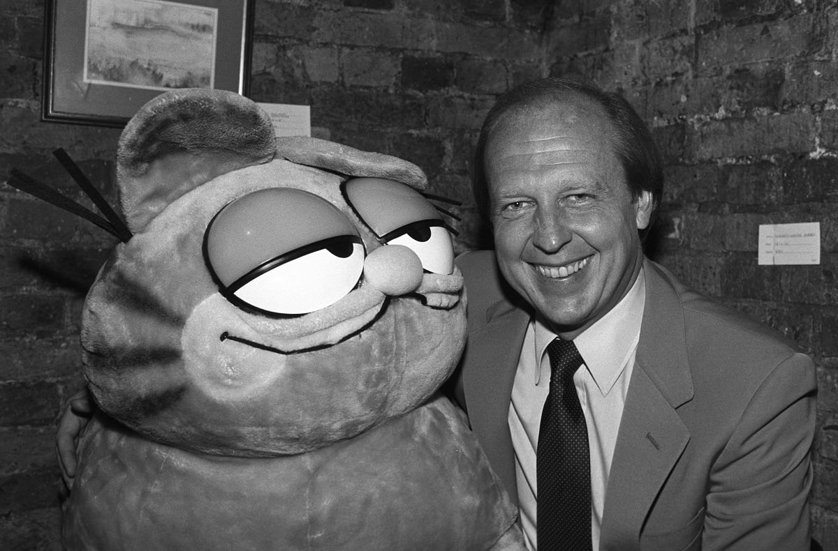 'Garfield' creator Jim Davis posing with a large doll of the cat in a black and white photo.