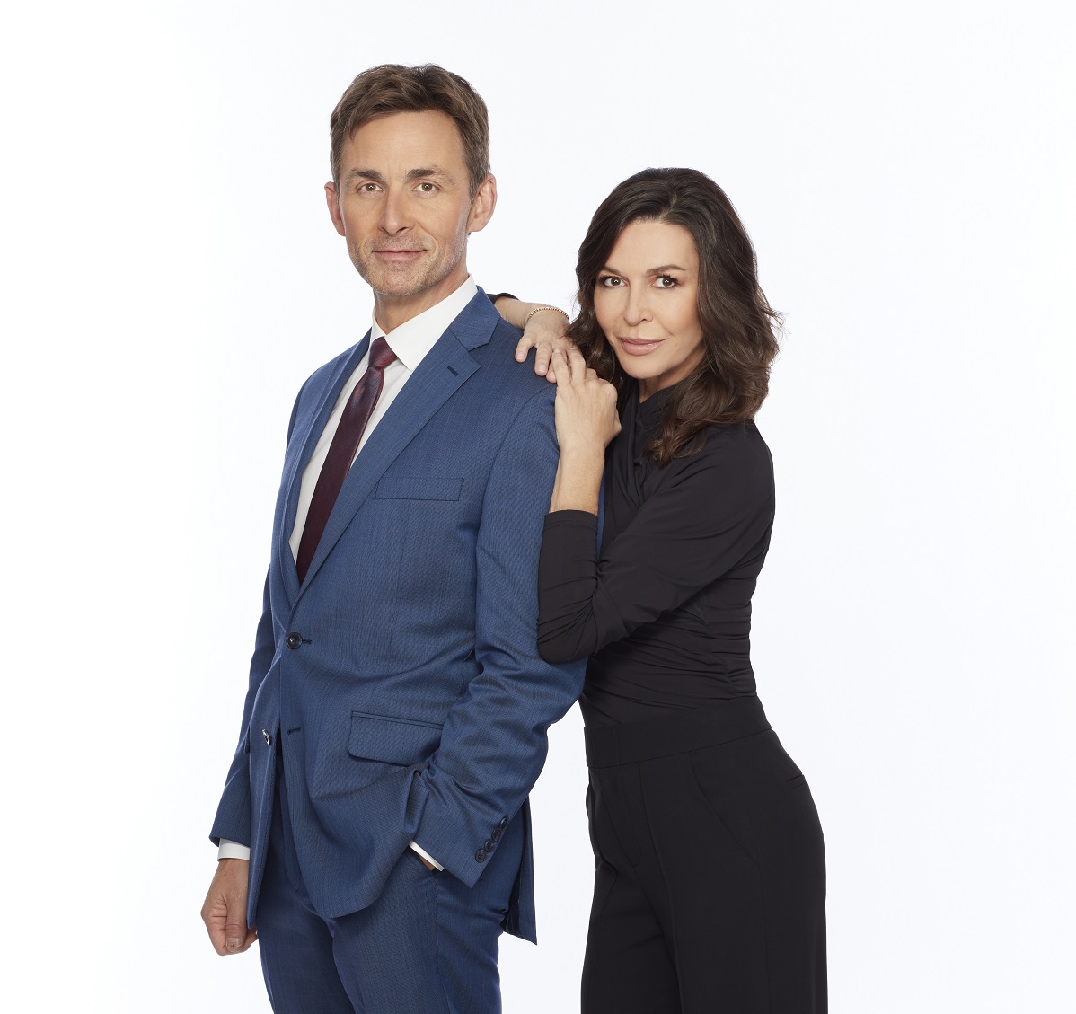 'General Hopsital' star James Patrick Stuart in a blue suit, and Finola Hughes in a black jumpsuit pose in front of a white backdrop.