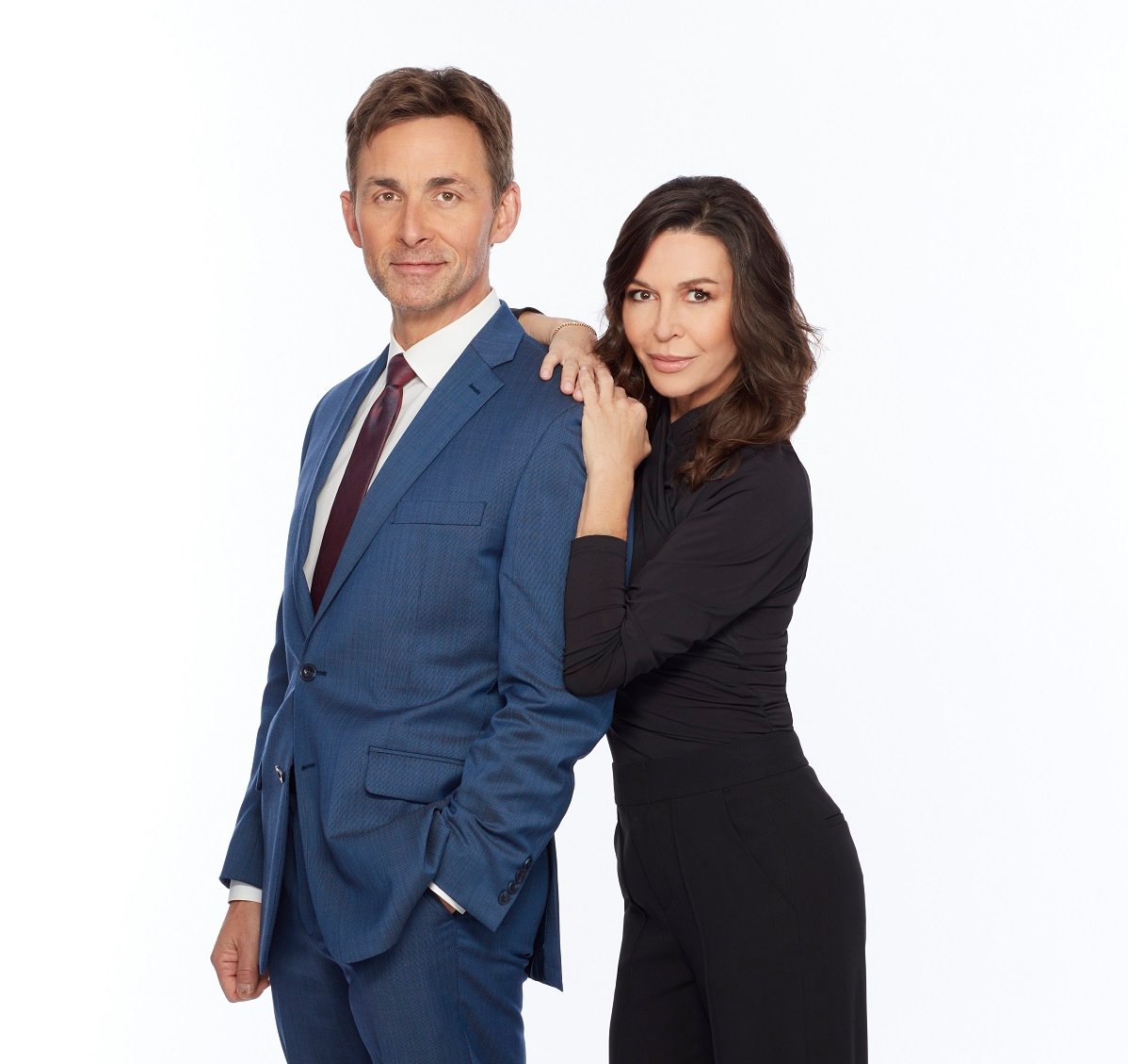 'General Hopsital' star James Patrick Stuart in a blue suit, and Finola Hughes in a black jumpsuit pose in front of a white backdrop.